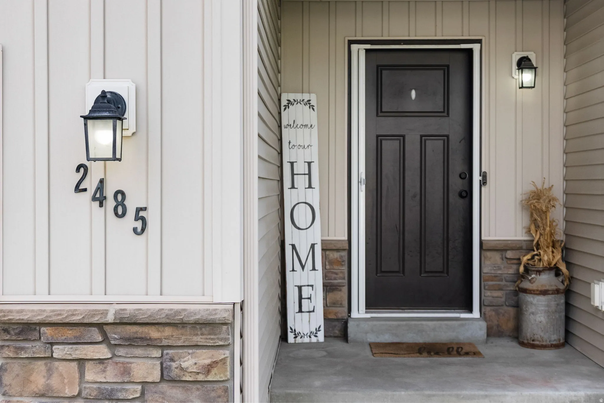 Cream-colored vertical siding exterior with a black panel-style entry door