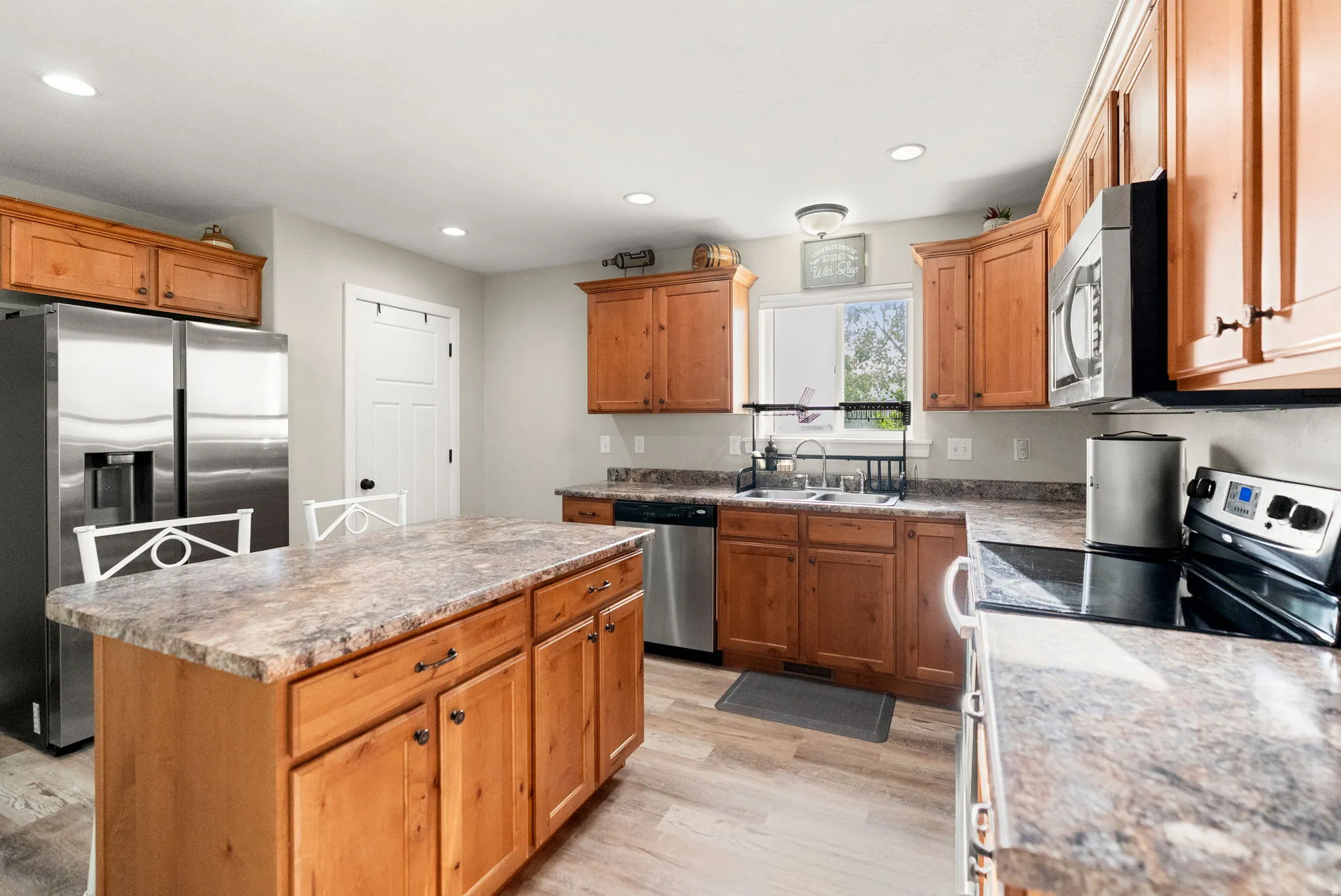 Kitchen featuring a central island, wood-finish cabinetry, stainless steel appliances, and wood-finish flooring
