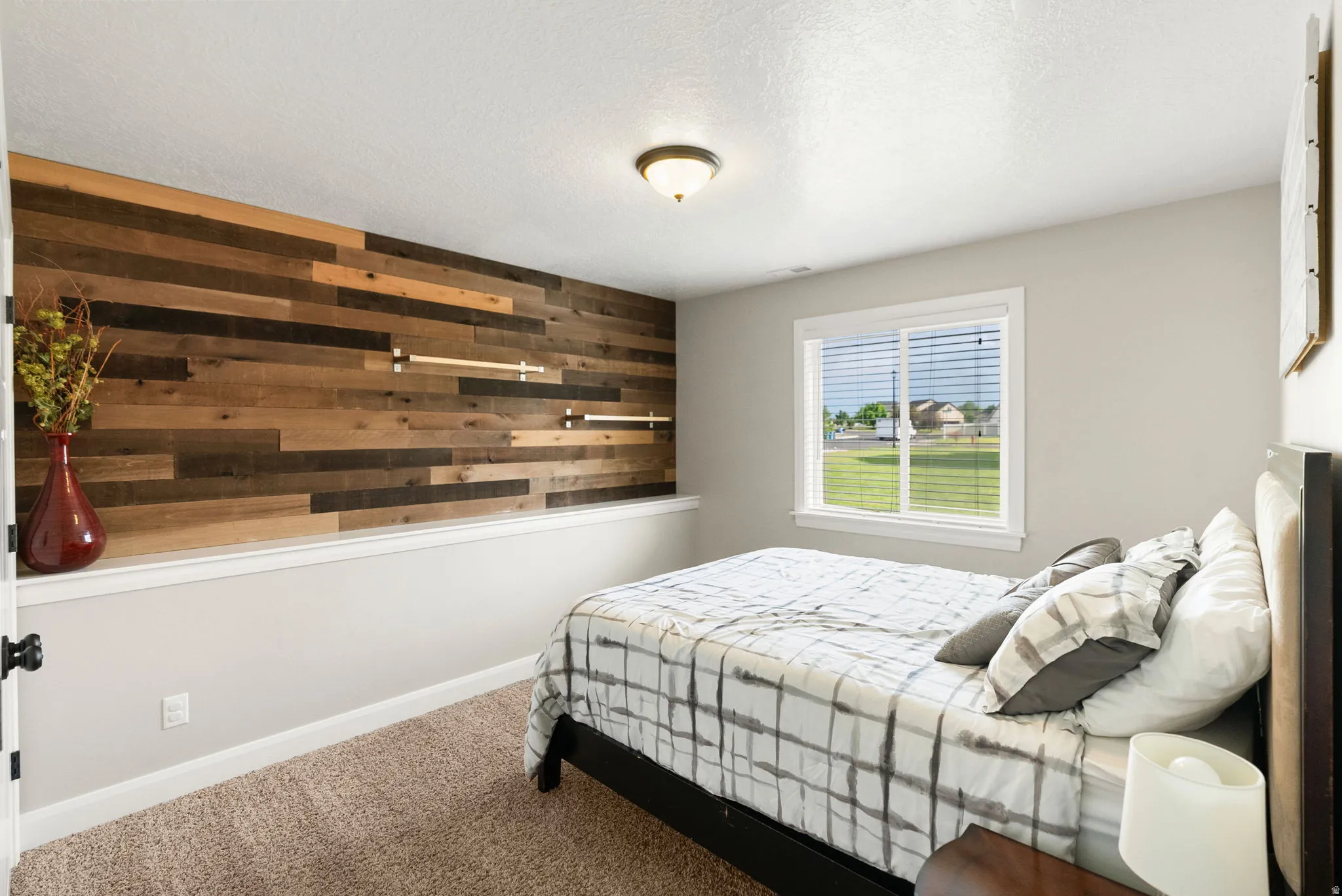 Bedroom featuring a plank-style accent wall, carpeted flooring, and a single window with blinds