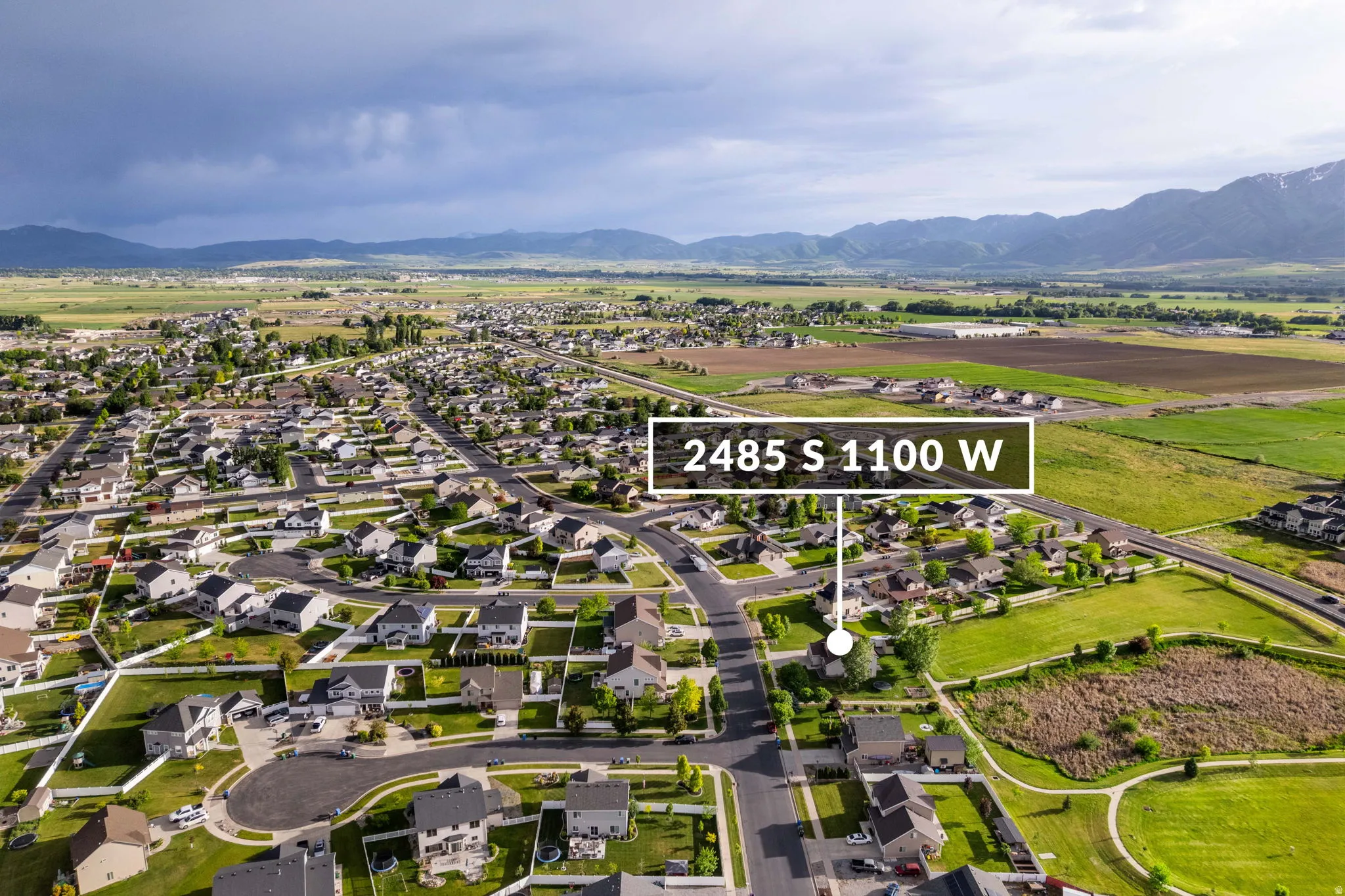 Aerial perspective showcasing a residential neighborhood with surrounding green spaces and distant mountains