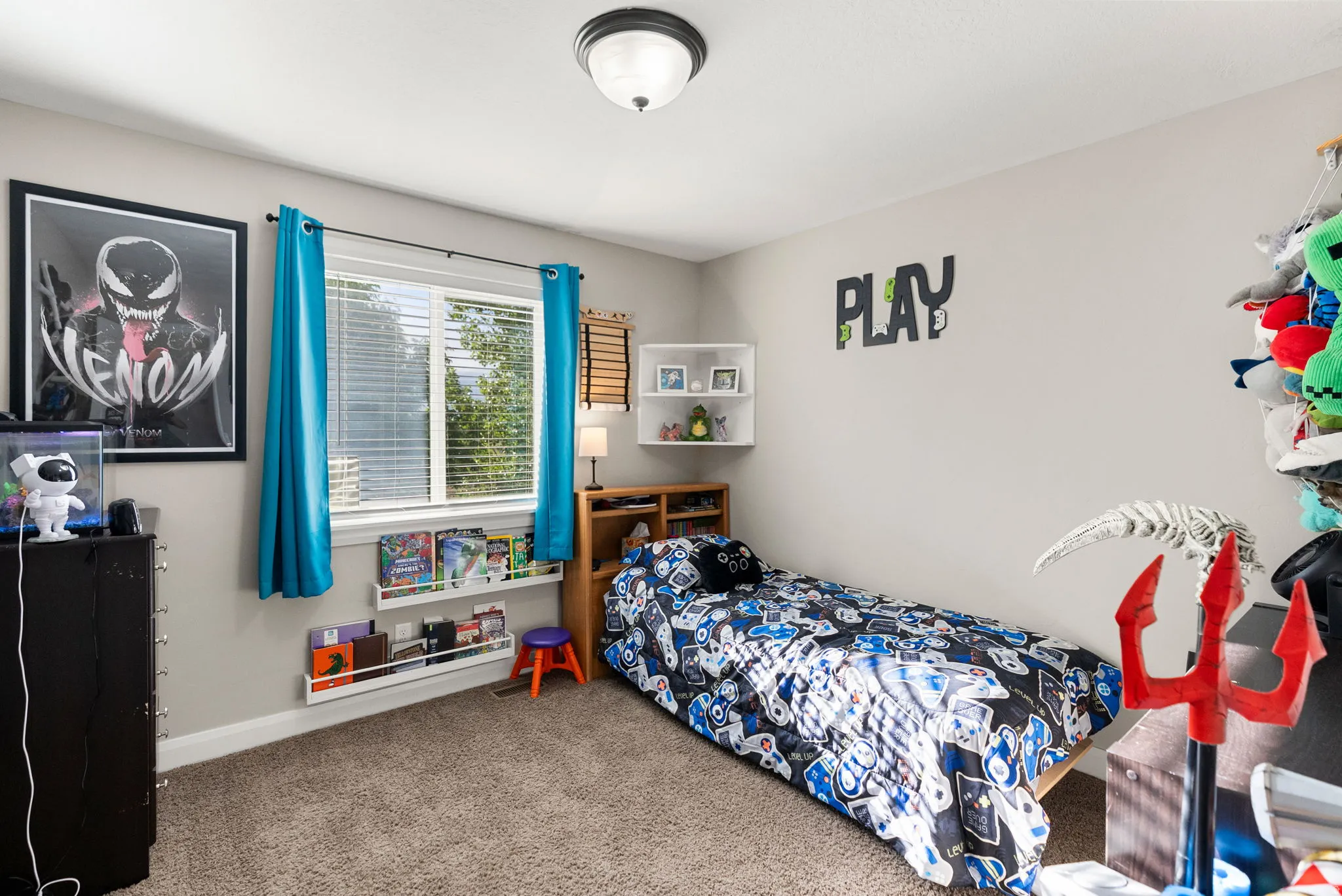 Carpeted bedroom featuring a large window with blinds, two white wall-mounted book ledges, and a ceiling-mounted light fixture