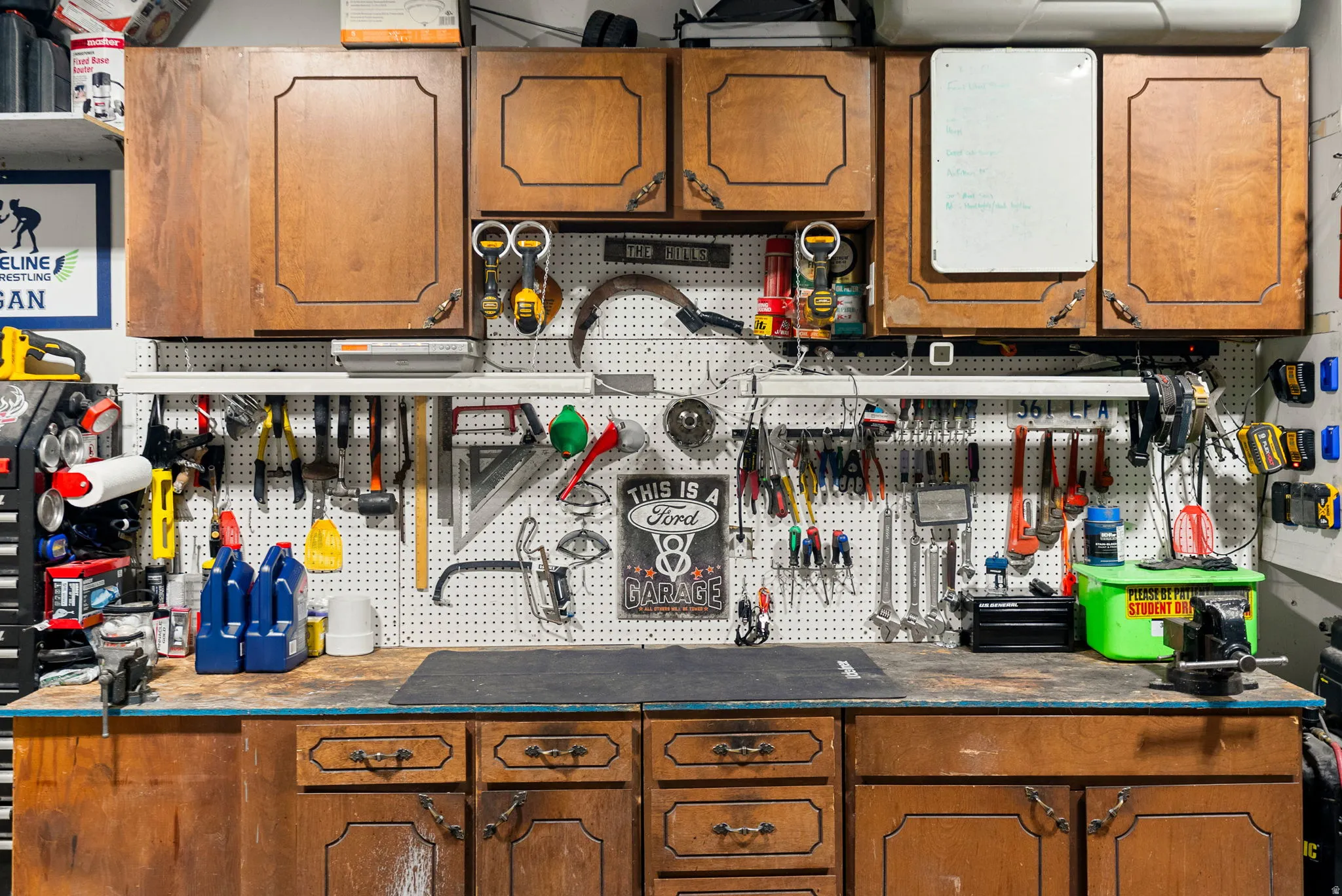 Functional workspace featuring wood-finish cabinetry, a white pegboard for organization, and a durable workbench surface