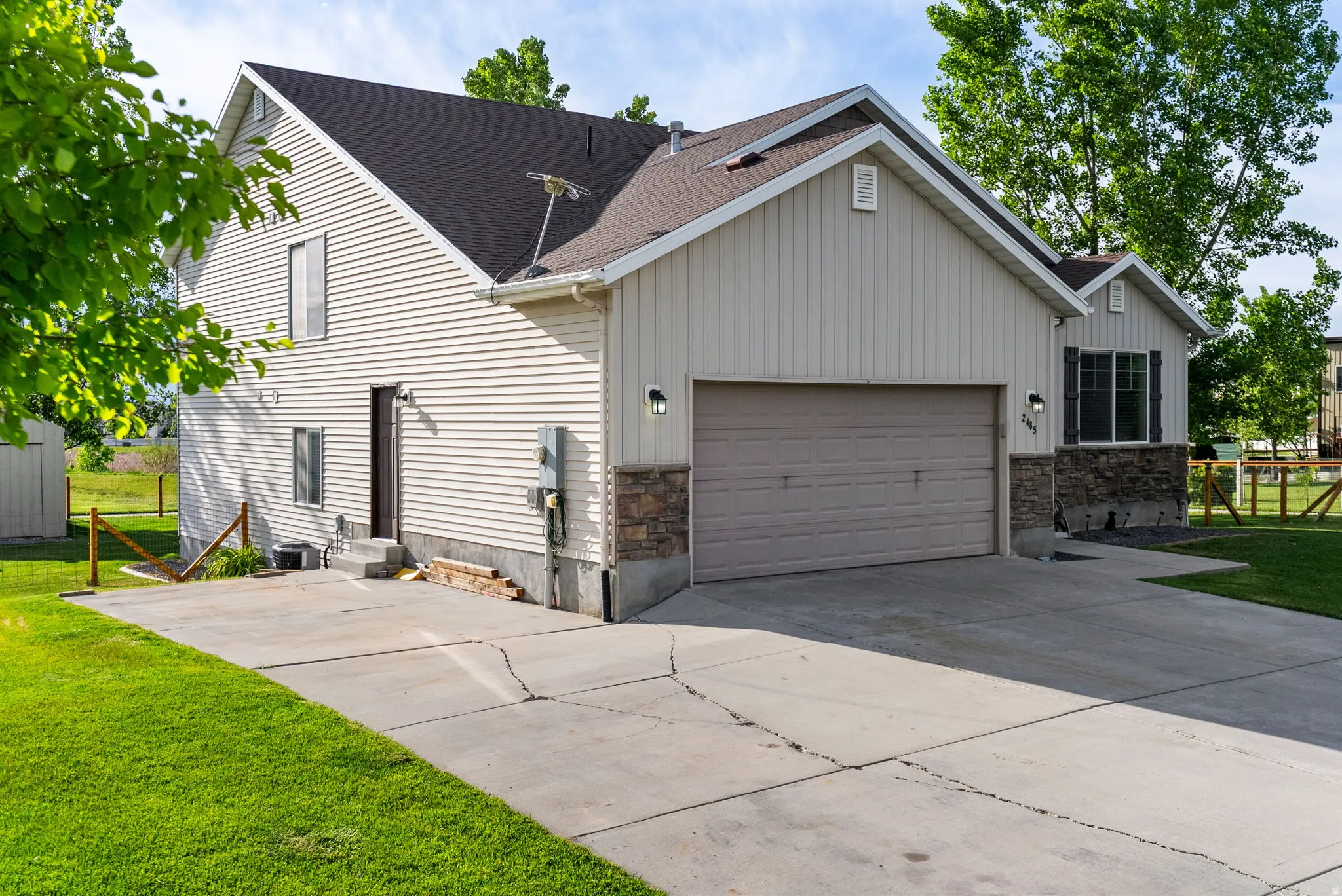 Exterior featuring light-colored horizontal siding, a dark roof, and a two-car garage with a complementary door