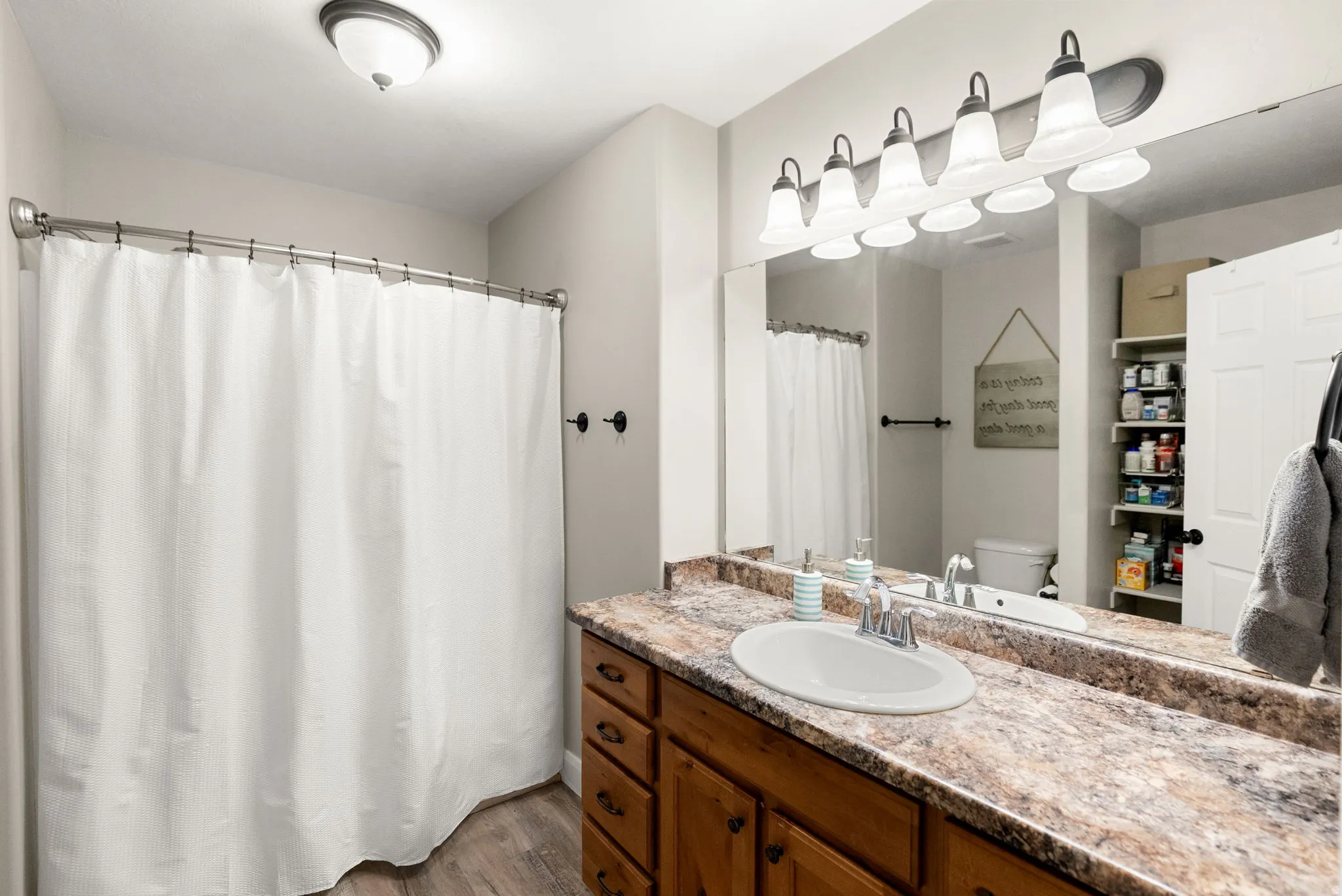 Bathroom featuring a single vanity with wood-finish cabinetry, a white basin, and a speckled countertop