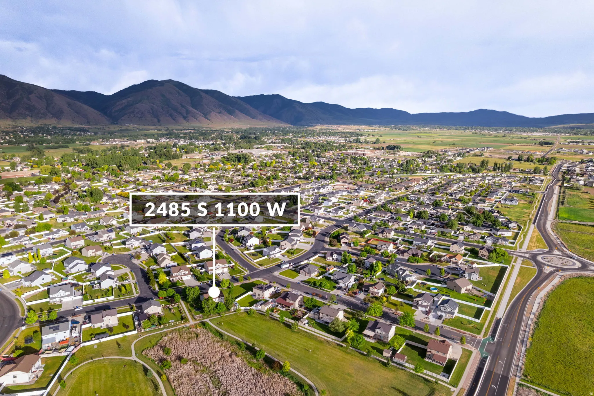 Aerial perspective showcasing a residential neighborhood with surrounding green spaces and distant mountains