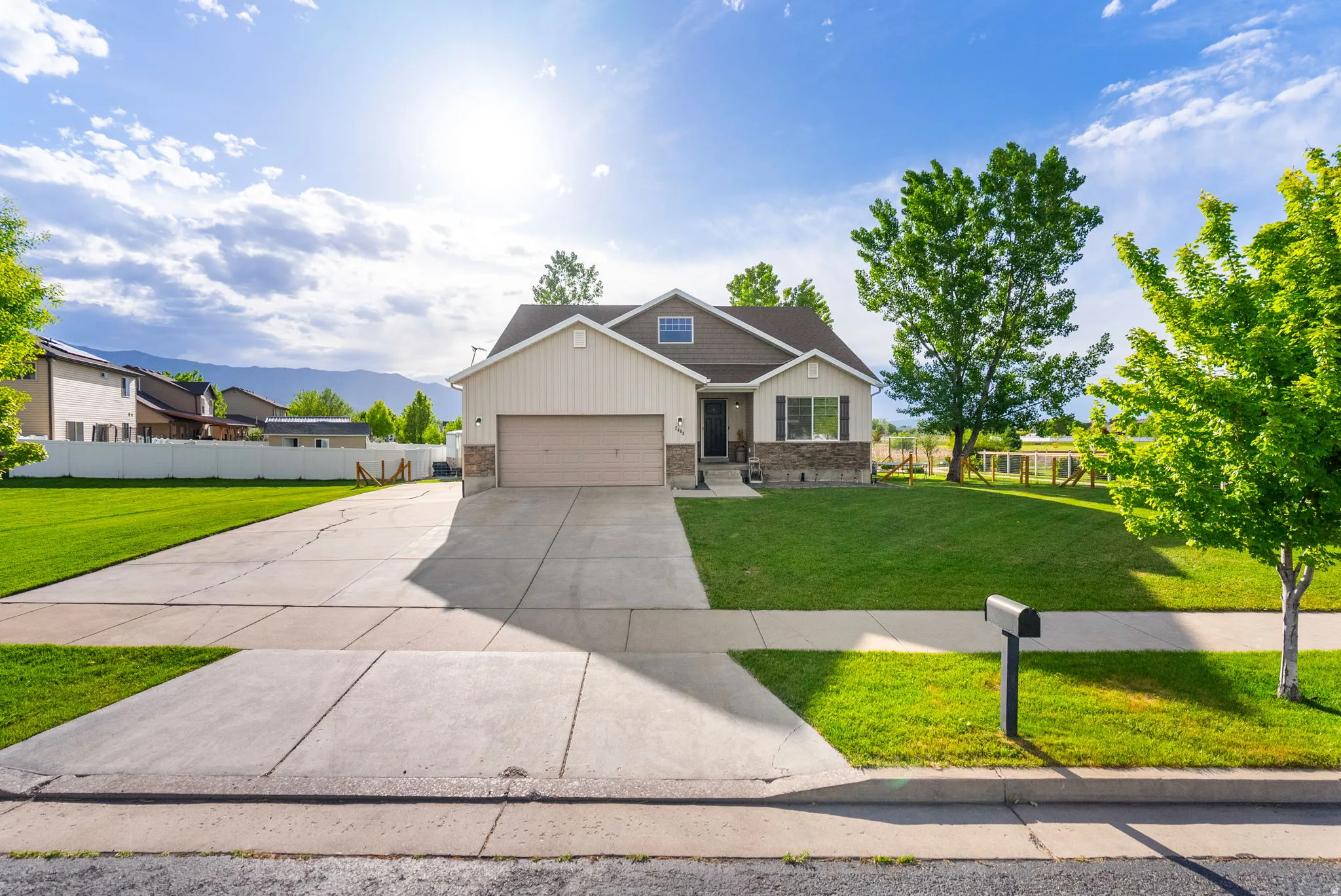 Contemporary single-family residence featuring a two-car garage, light-colored siding, and stone accents