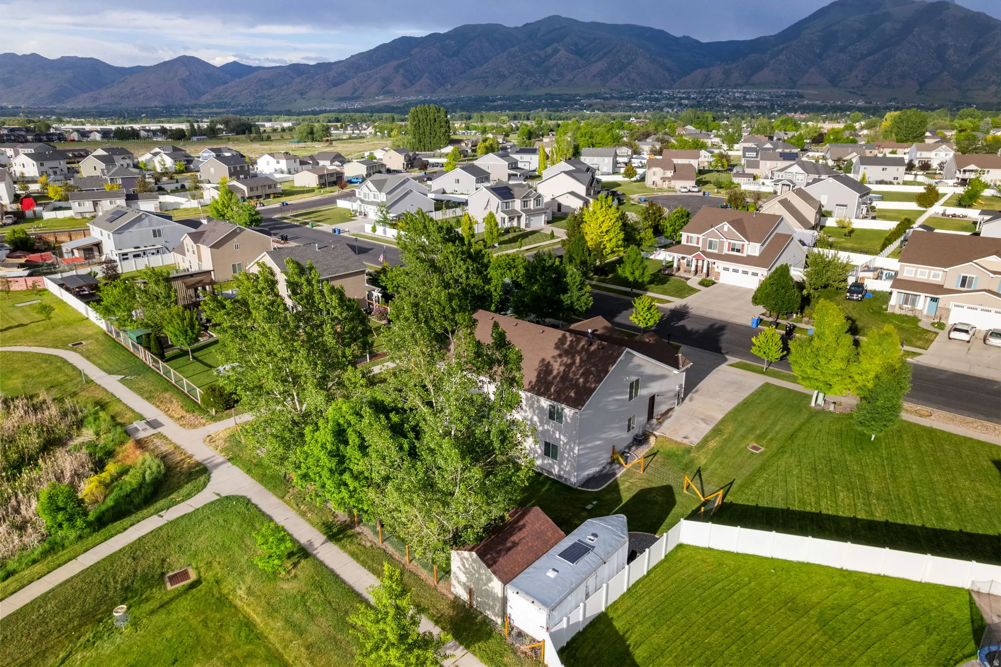 Residential neighborhood featuring a paved pathway system, mature trees, and mountain backdrop