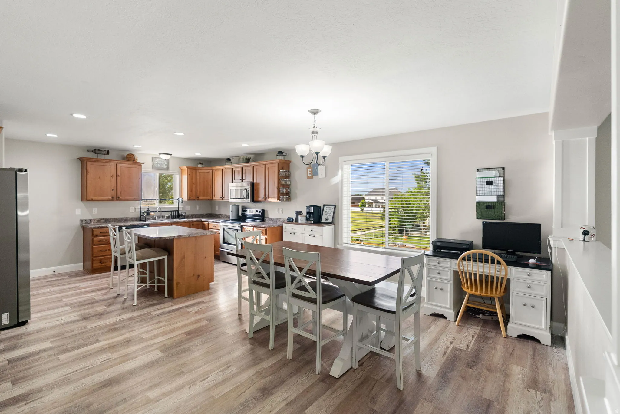 Open-concept kitchen featuring wood-finish flooring, recessed lighting, and a kitchen island with seating