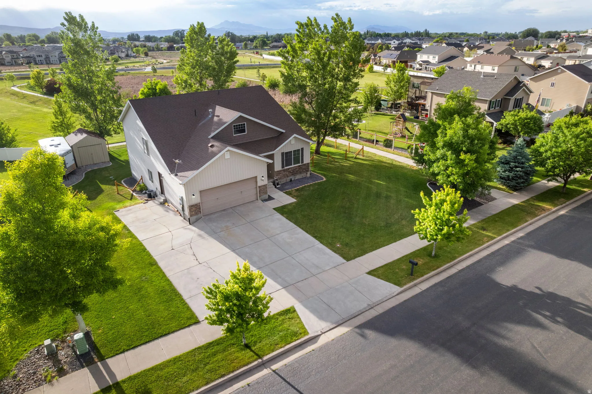 Two-story property featuring a front-facing attached garage, stone and siding exterior accents, and a paved driveway