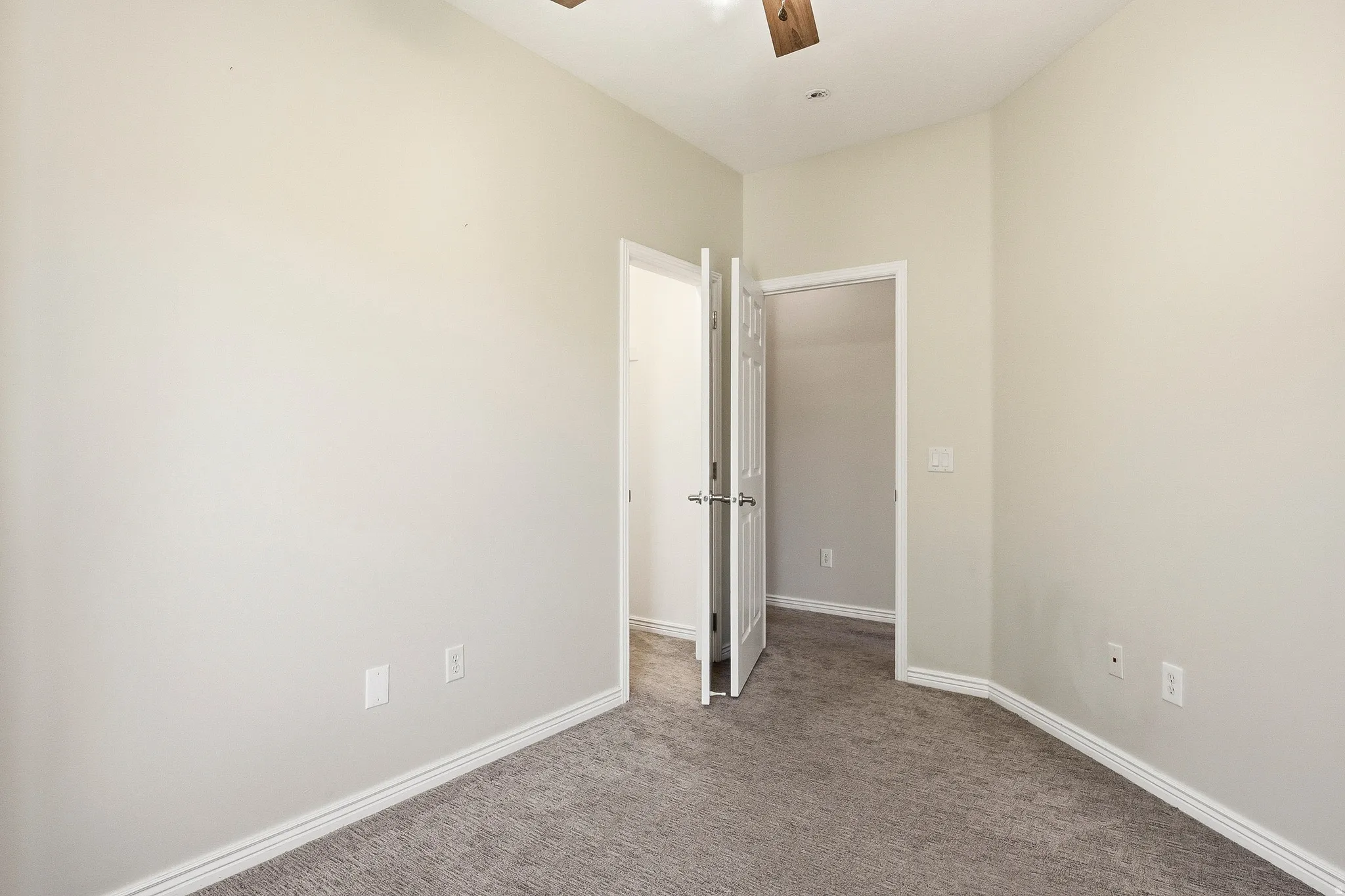 Carpeted room with vaulted ceilings and a ceiling fan