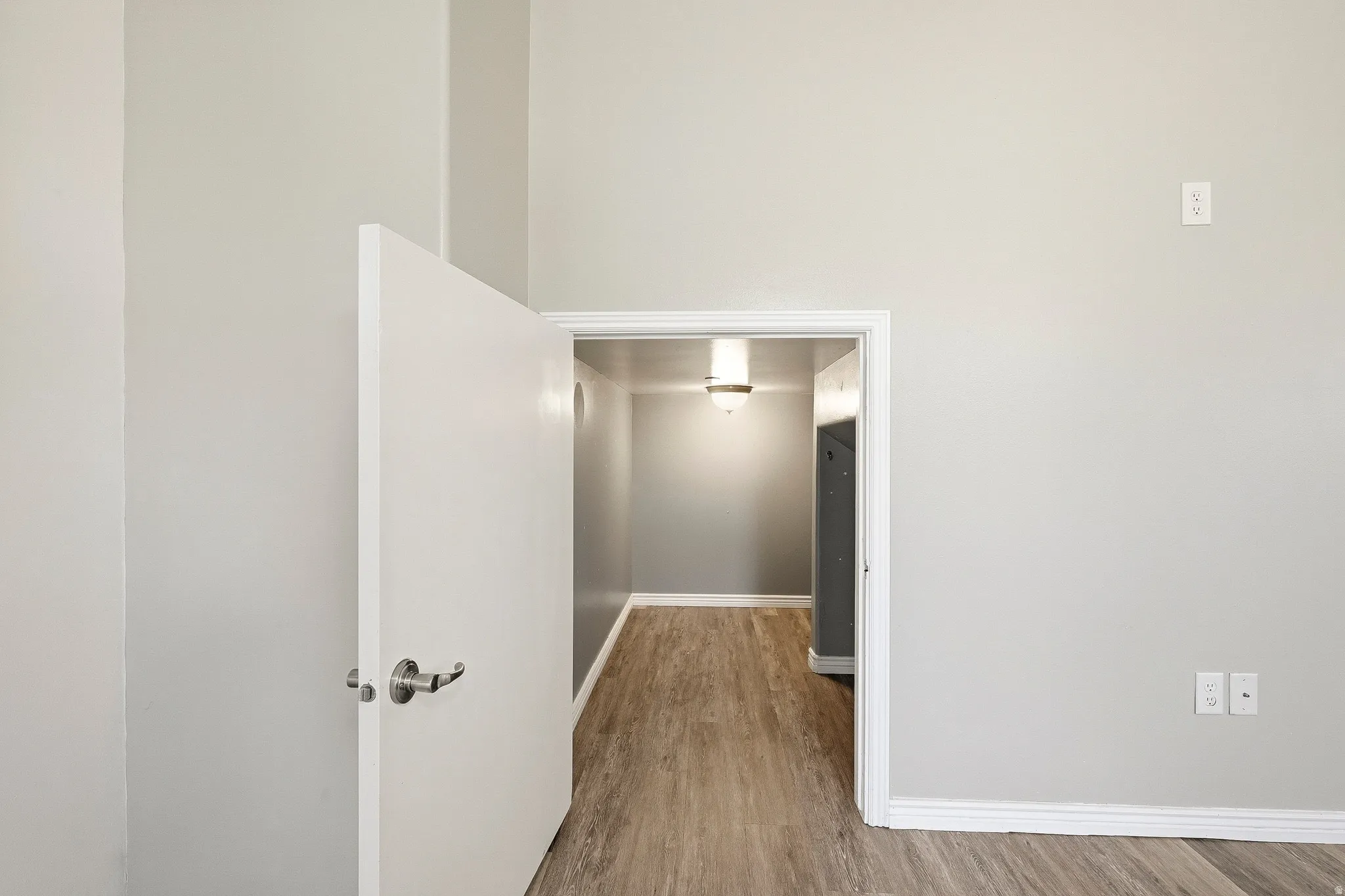 Interior hallway featuring wood-finish flooring, light grey painted walls, and white trim molding
