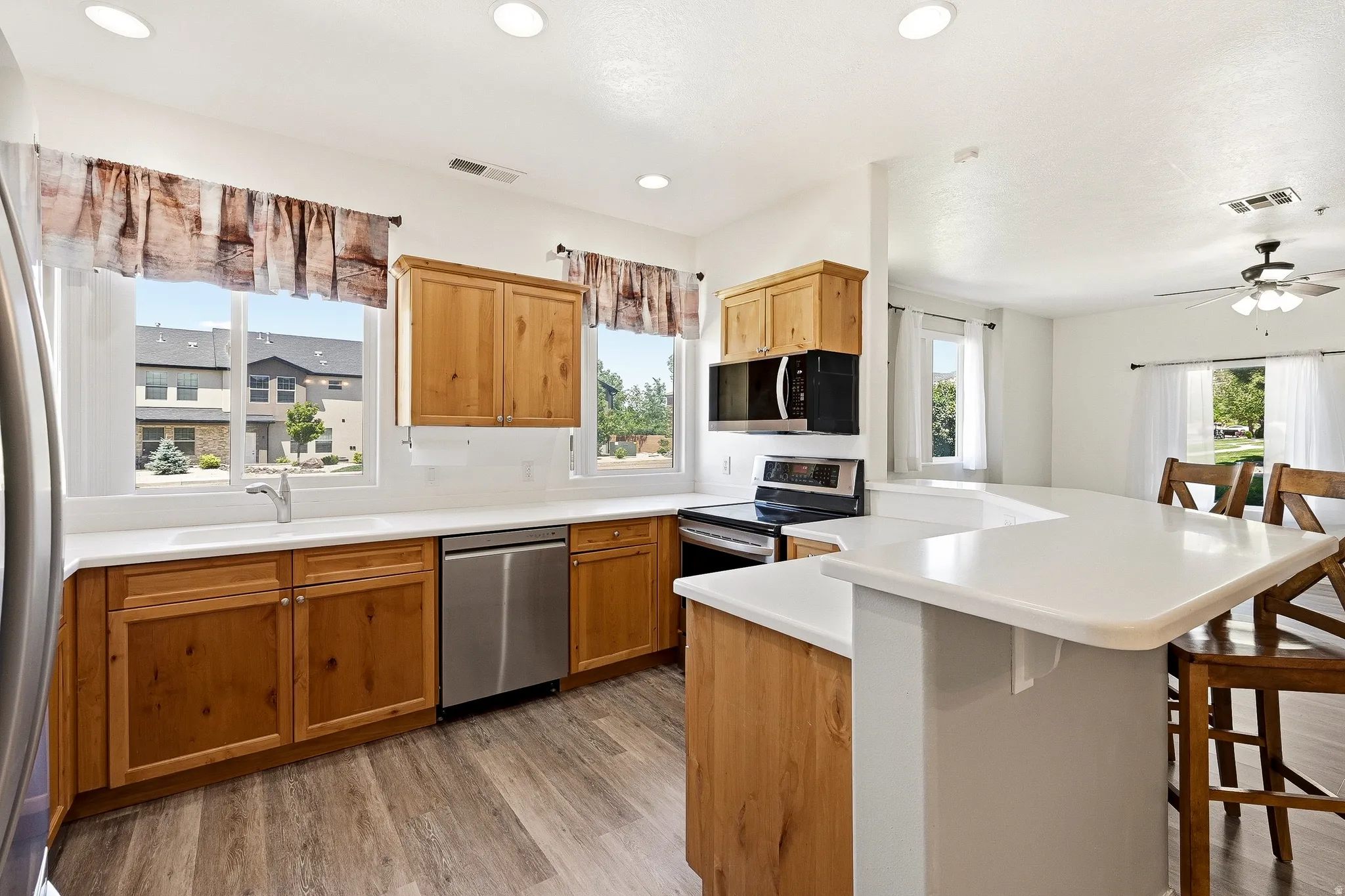 Kitchen featuring wood cabinetry, stainless steel appliances, white countertops, and wood-finish flooring