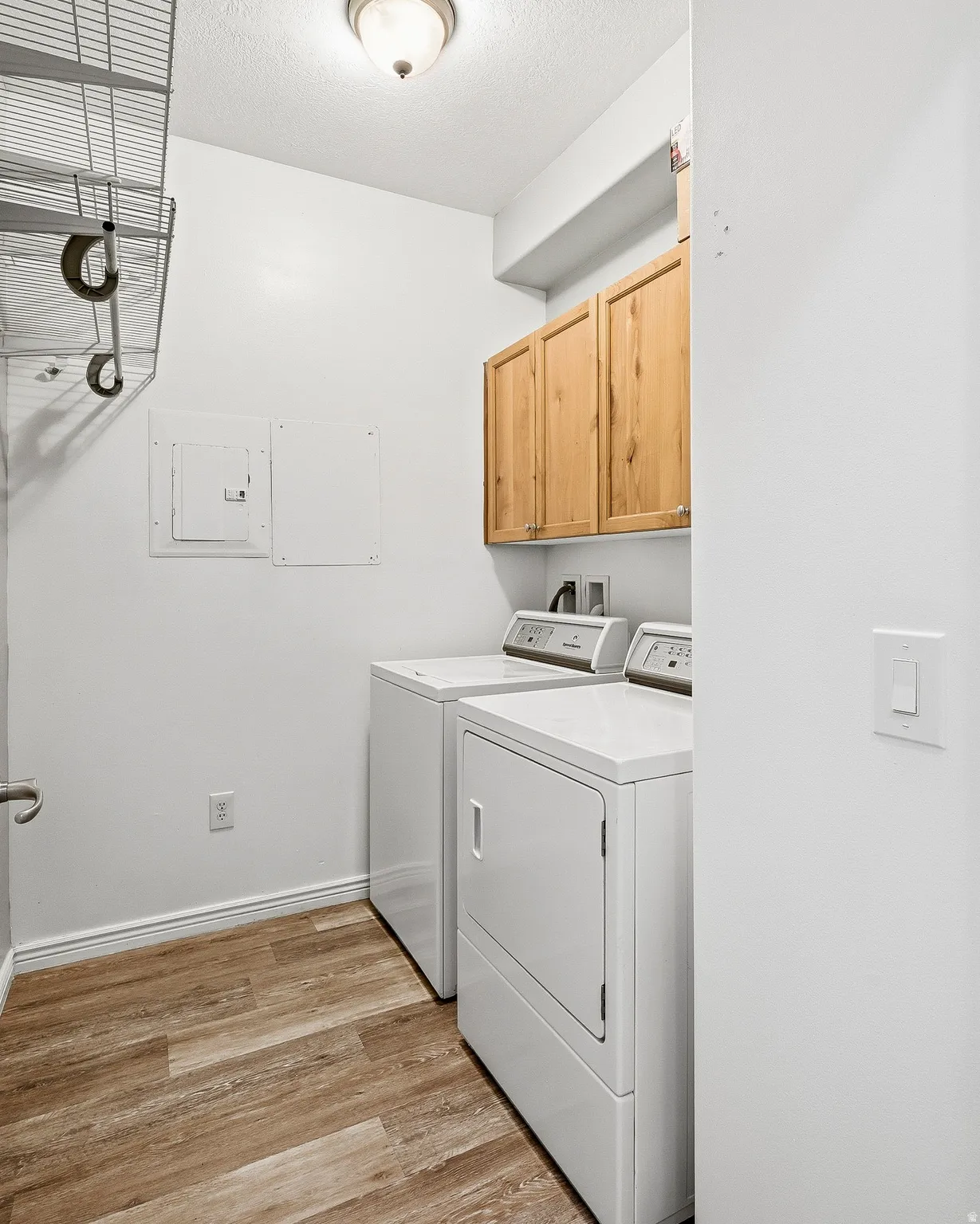 Dedicated laundry area featuring wood-finish flooring and integrated cabinetry