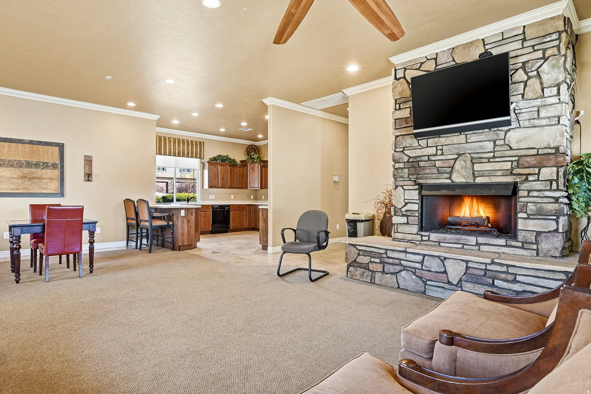 Spacious living area featuring a floor-to-ceiling stone fireplace, recessed lighting, and crown molding
