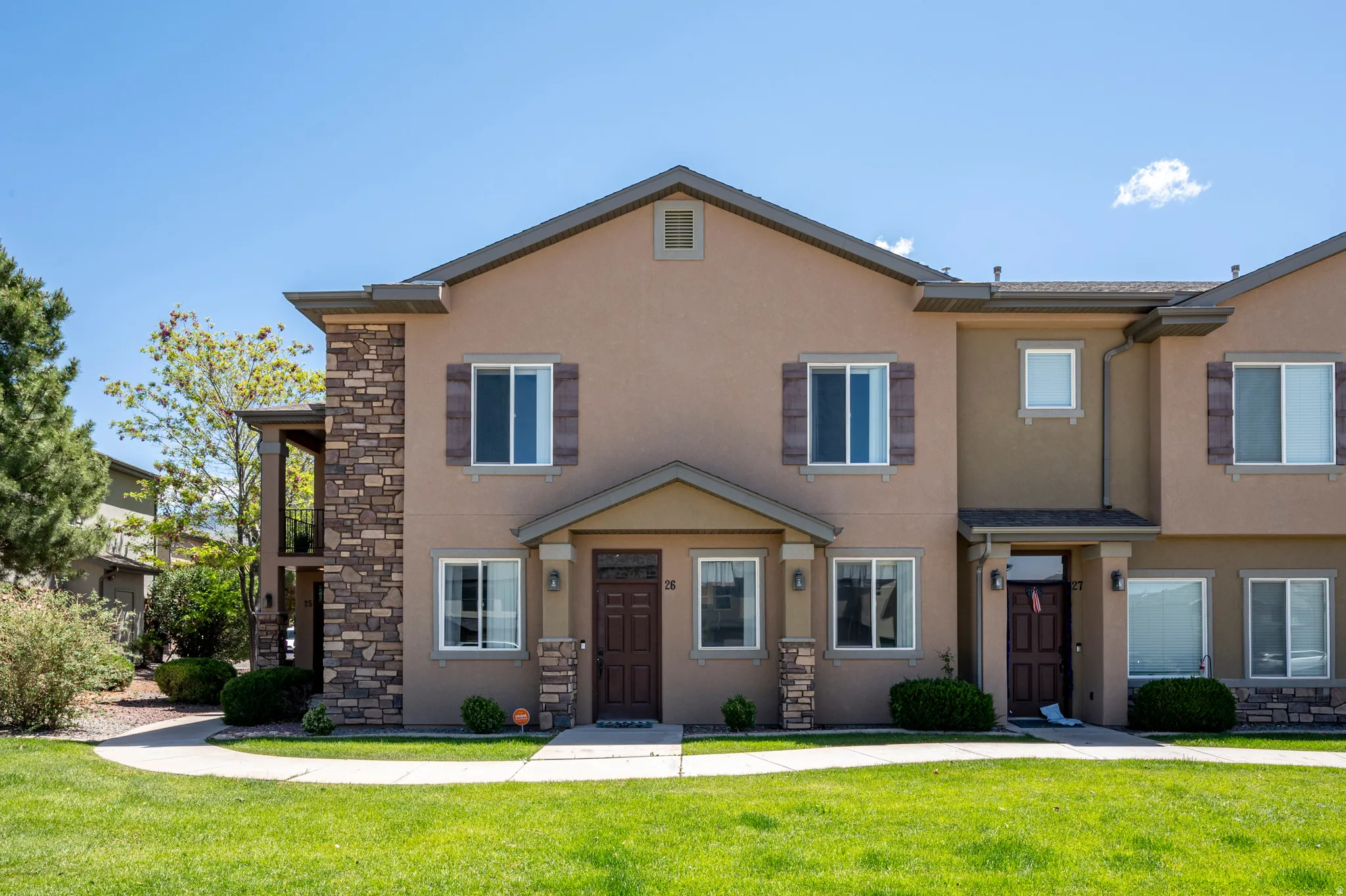 Stucco exterior featuring stone accents, dark wood-finish shutters, and multiple windows