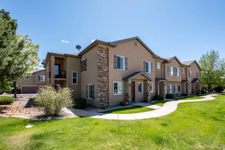 Multi-story townhome exterior featuring stucco siding and stone accents