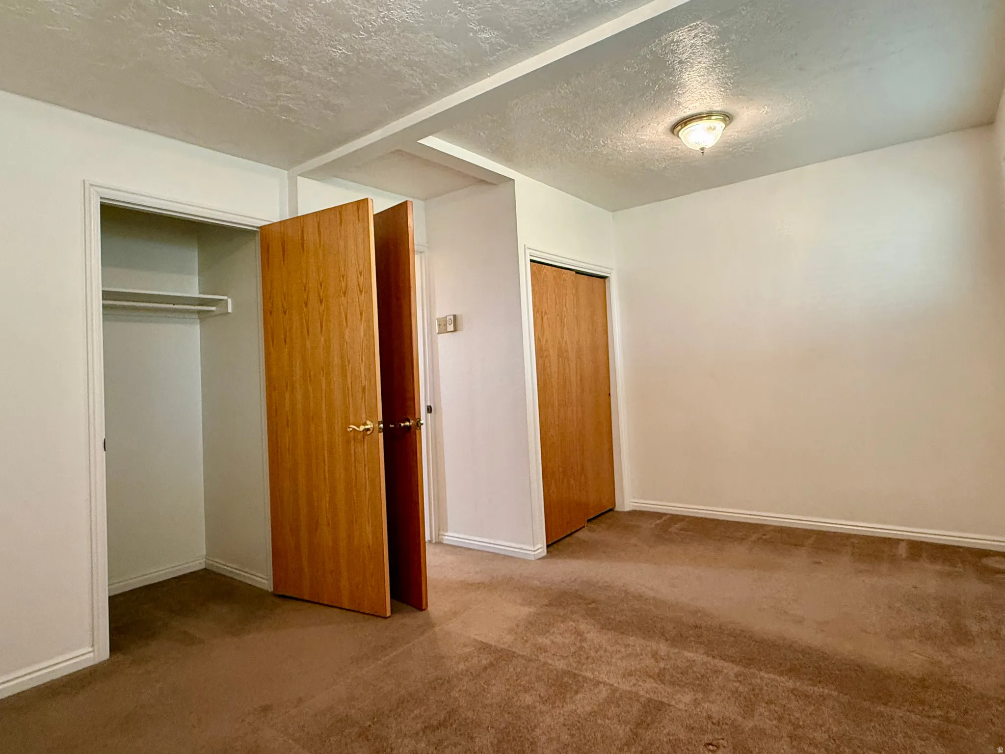 Room featuring neutral carpeting, white walls, and a textured ceiling