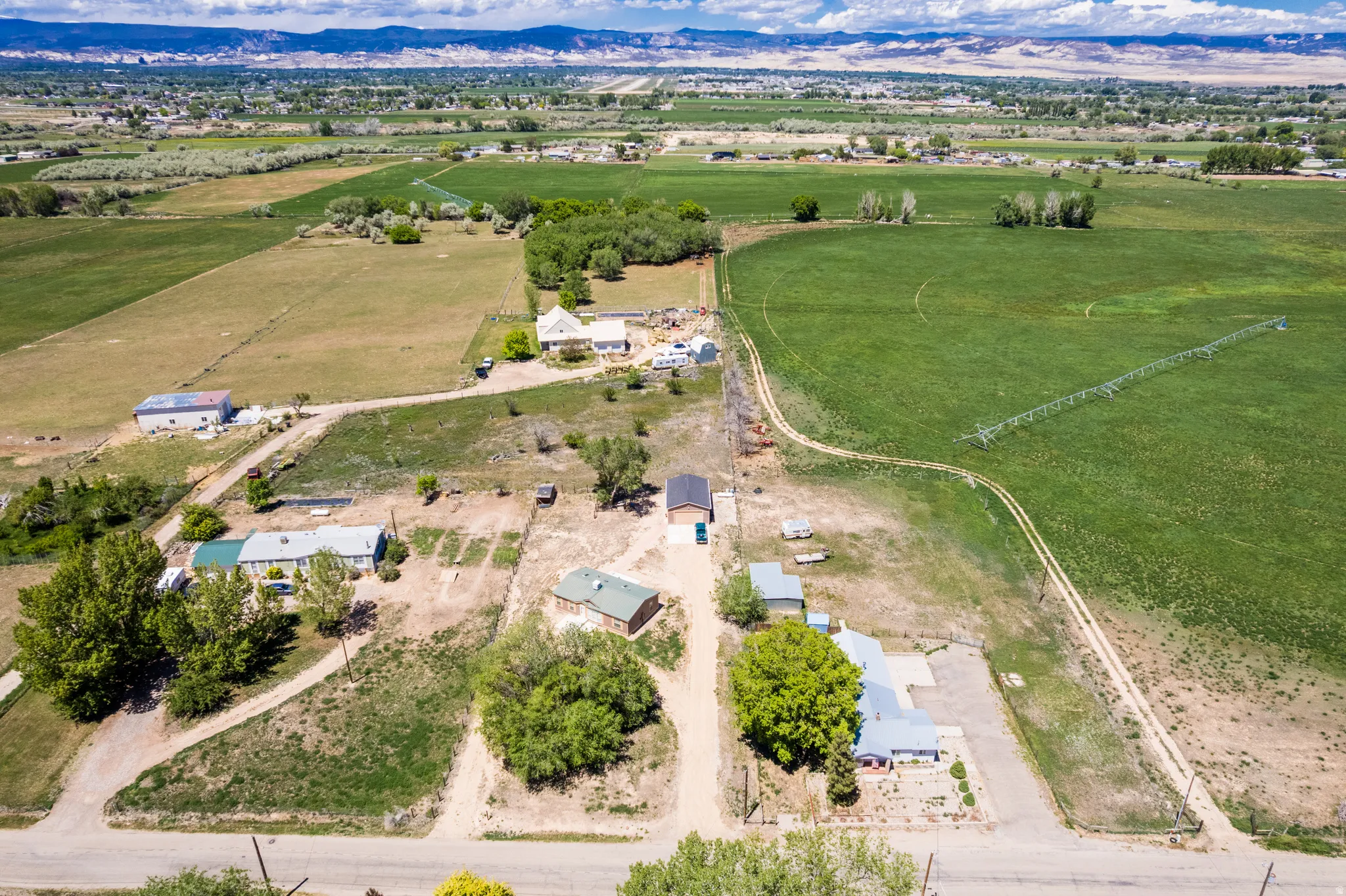 Expansive land parcel featuring multiple residential structures, agricultural fields, and a distant mountain range