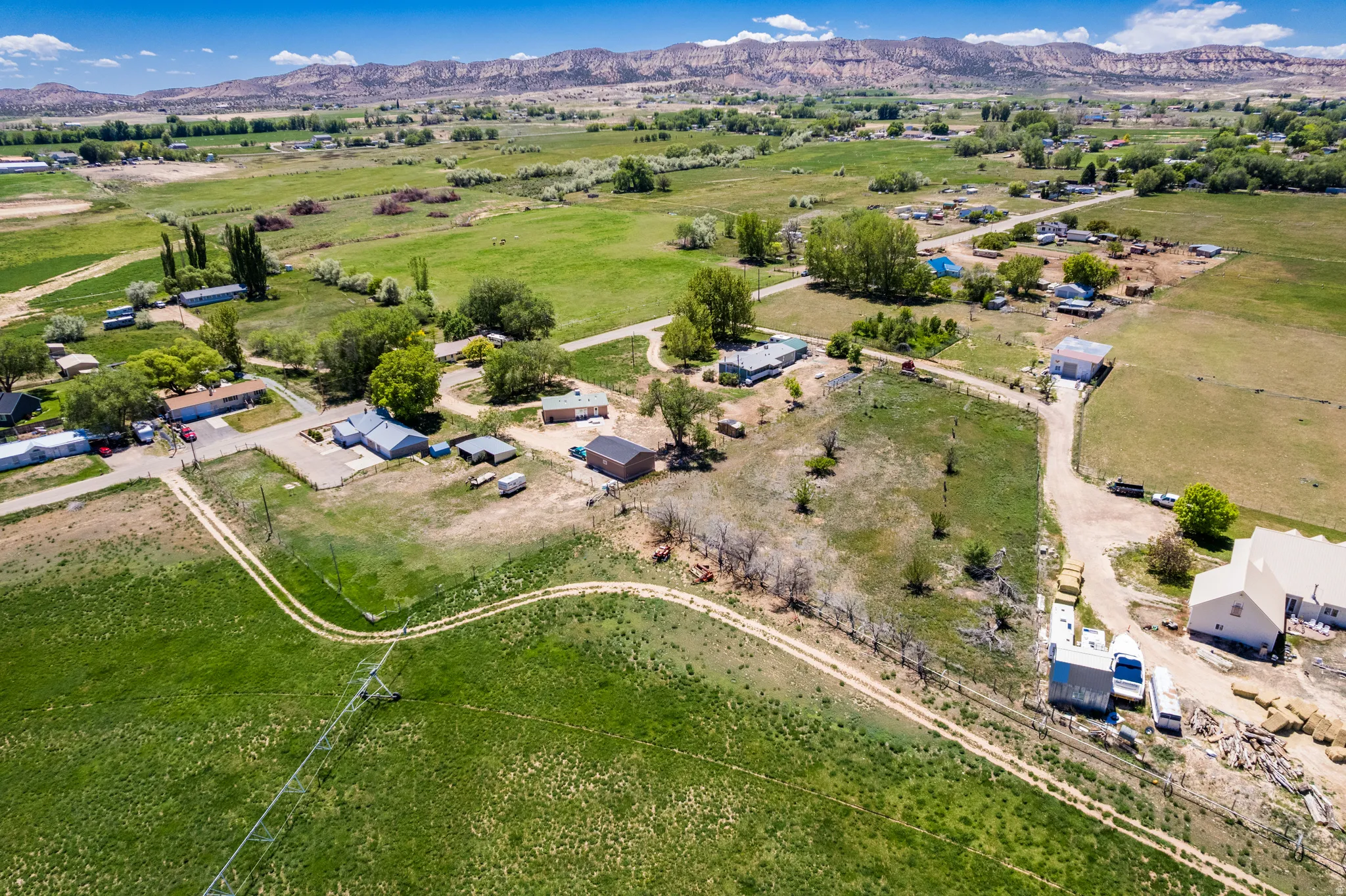 Expansive rural landscape featuring multiple dwellings and agricultural buildings amidst green fields