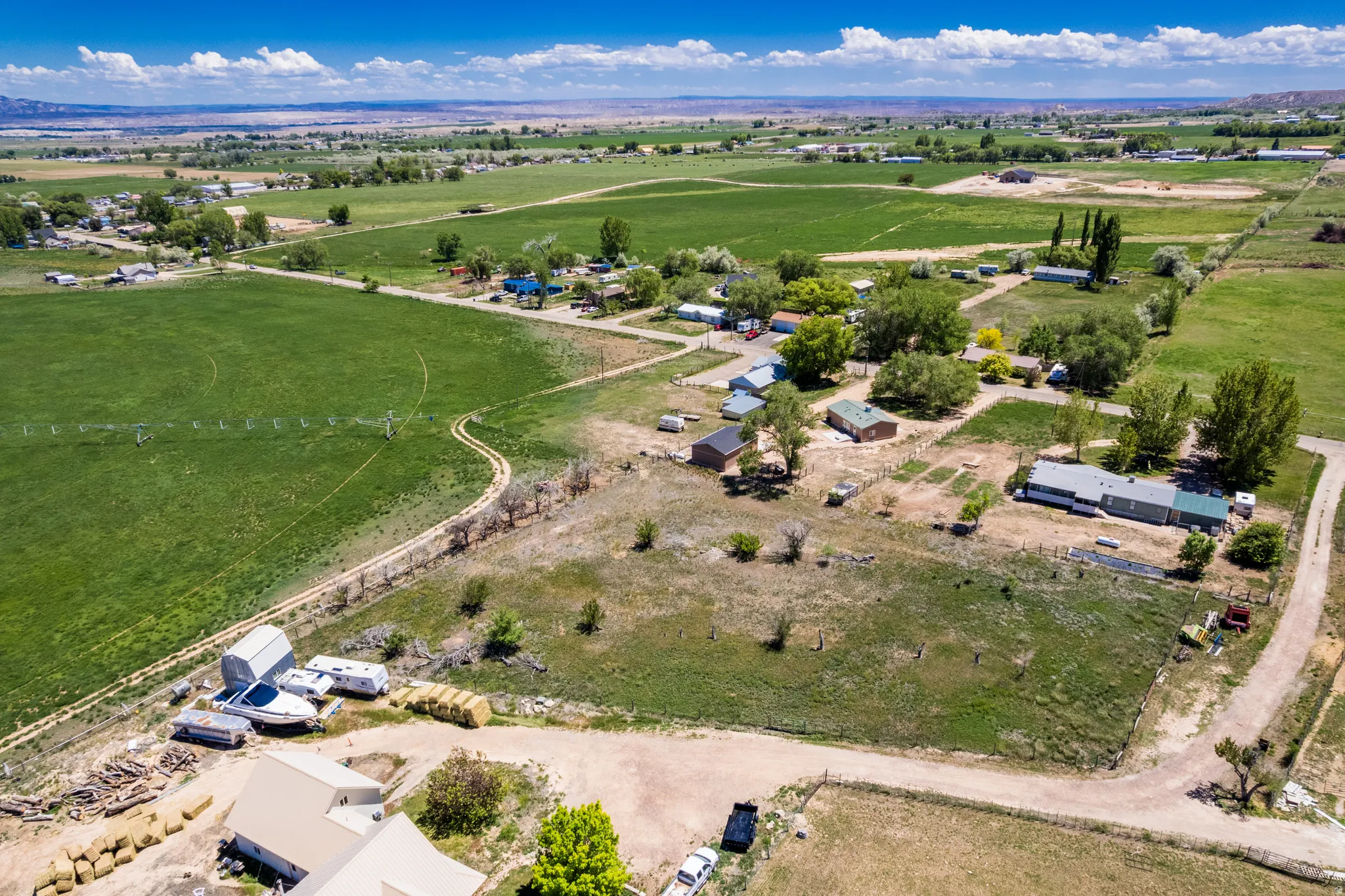 Expansive agricultural landscape featuring large green fields and scattered residential properties
