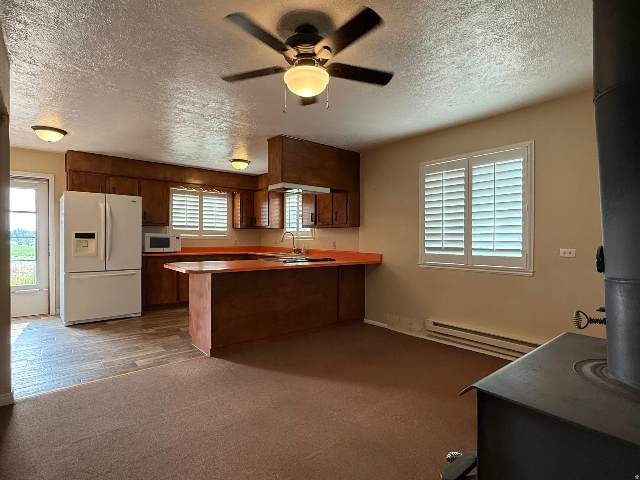 Spacious kitchen area featuring wood-finish cabinetry, an integrated breakfast bar, and wood-finish flooring