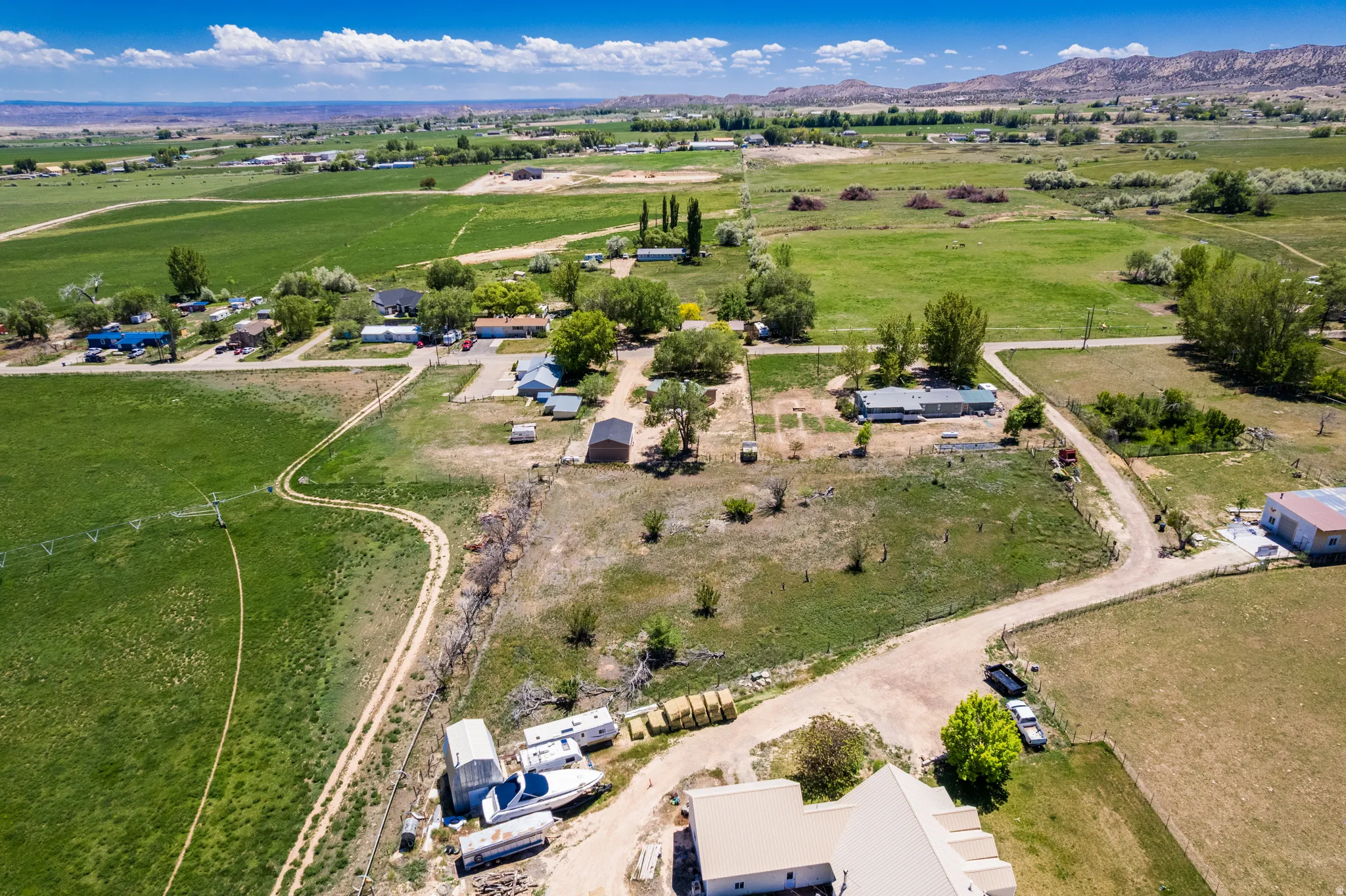 Expansive rural property featuring a mix of green agricultural fields, scattered residential structures, and mature trees