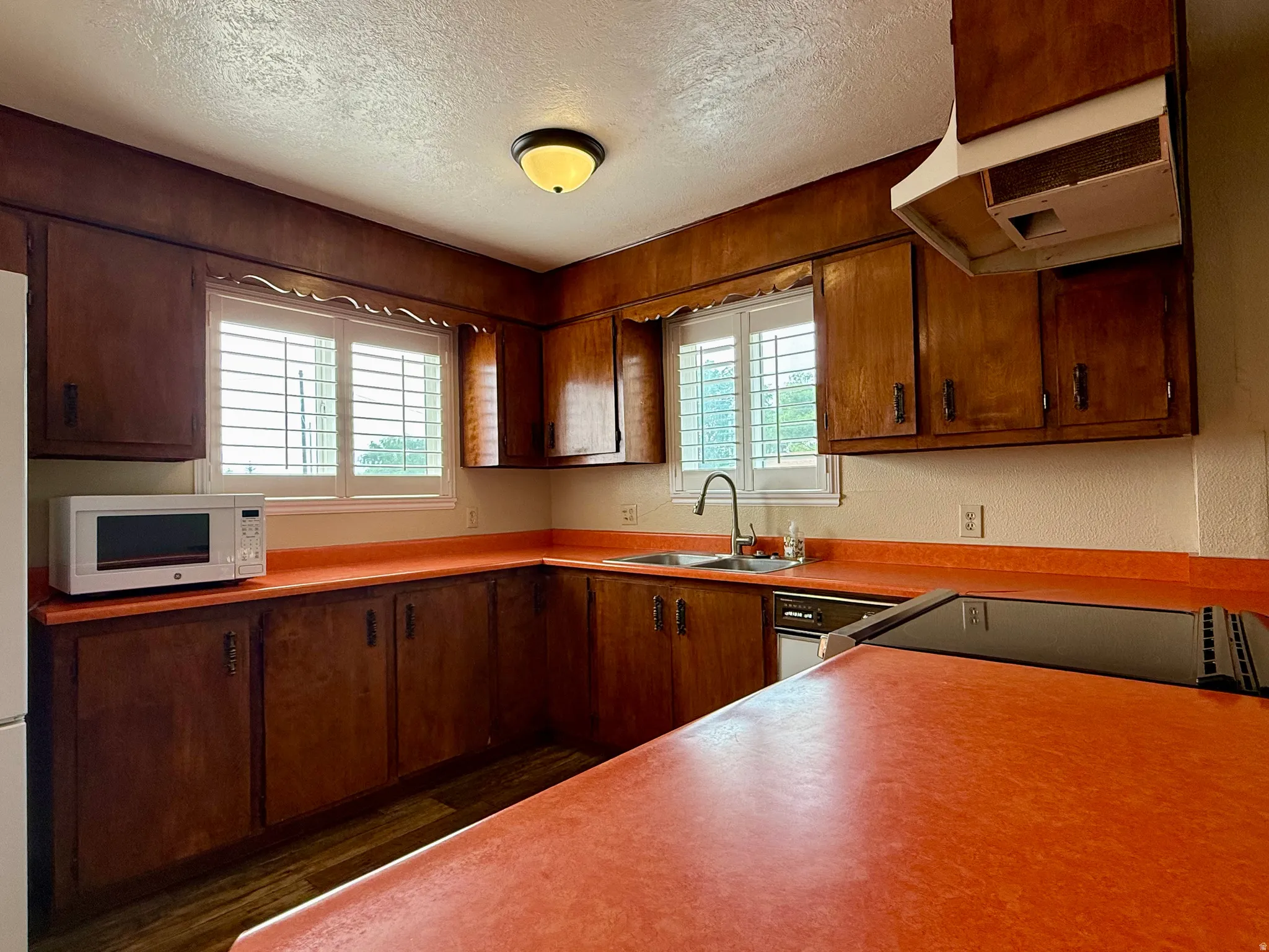 Kitchen featuring wood cabinetry, orange countertops, and a white plantation shutter window