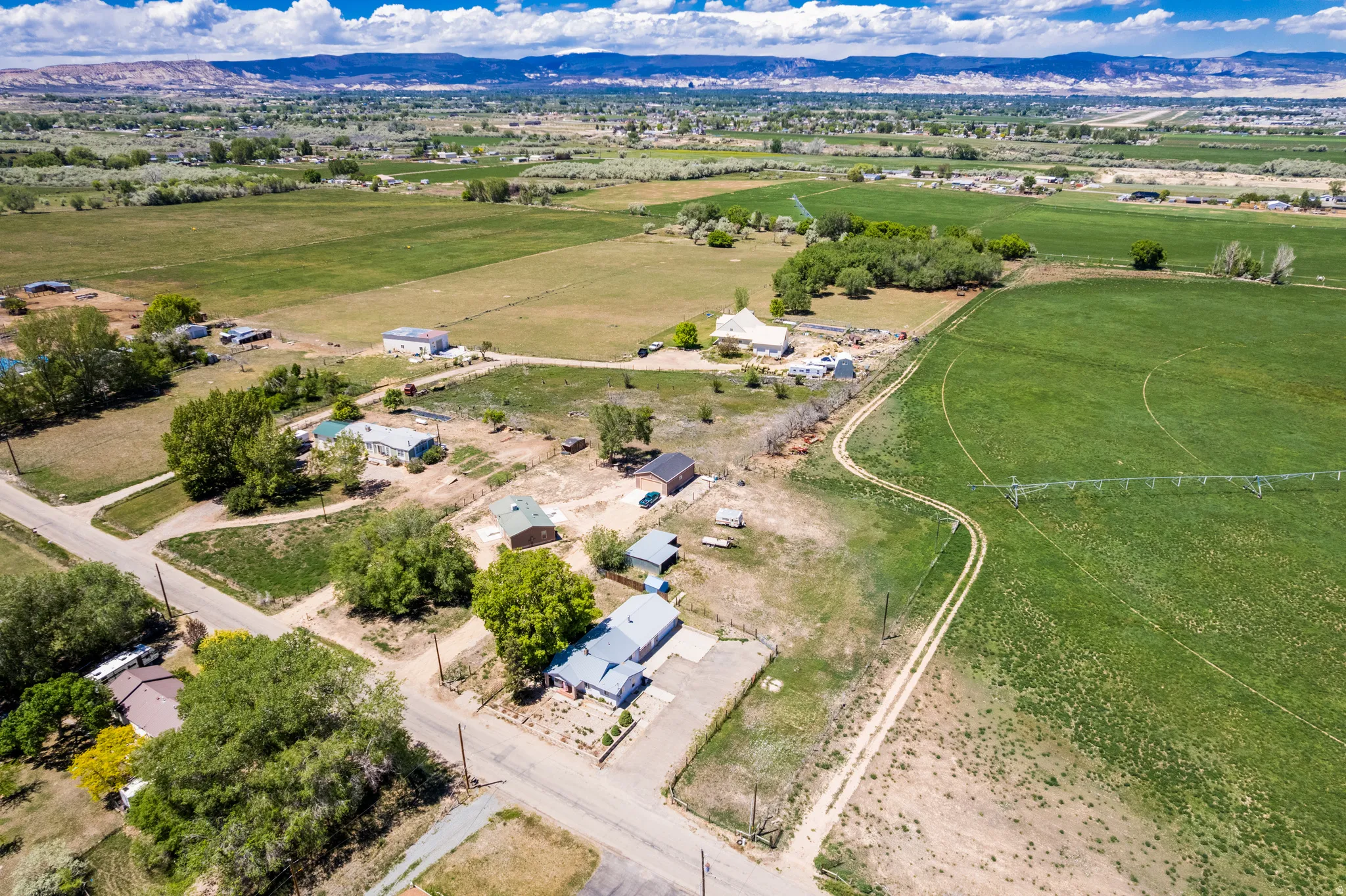 Expansive aerial capturing multiple properties amidst agricultural fields and distant mountain ranges