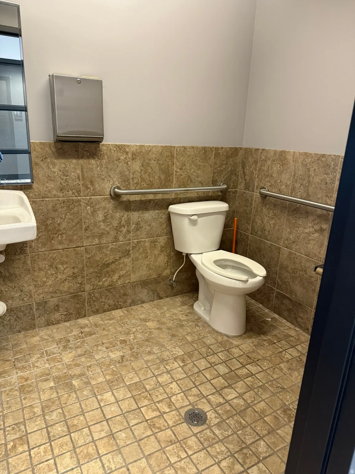 Restroom featuring a wall-mounted sink, ceramic tile flooring, and wall-mounted grab bars