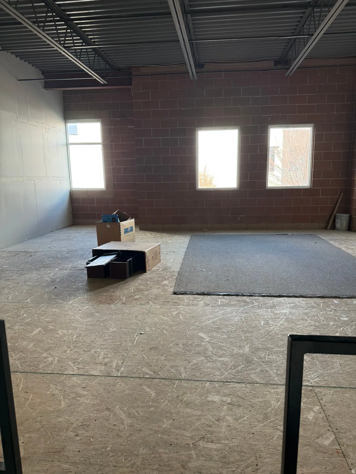 Spacious interior with exposed ceiling joists and brick wall
