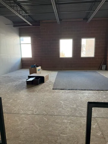 Spacious interior with exposed ceiling joists and brick wall