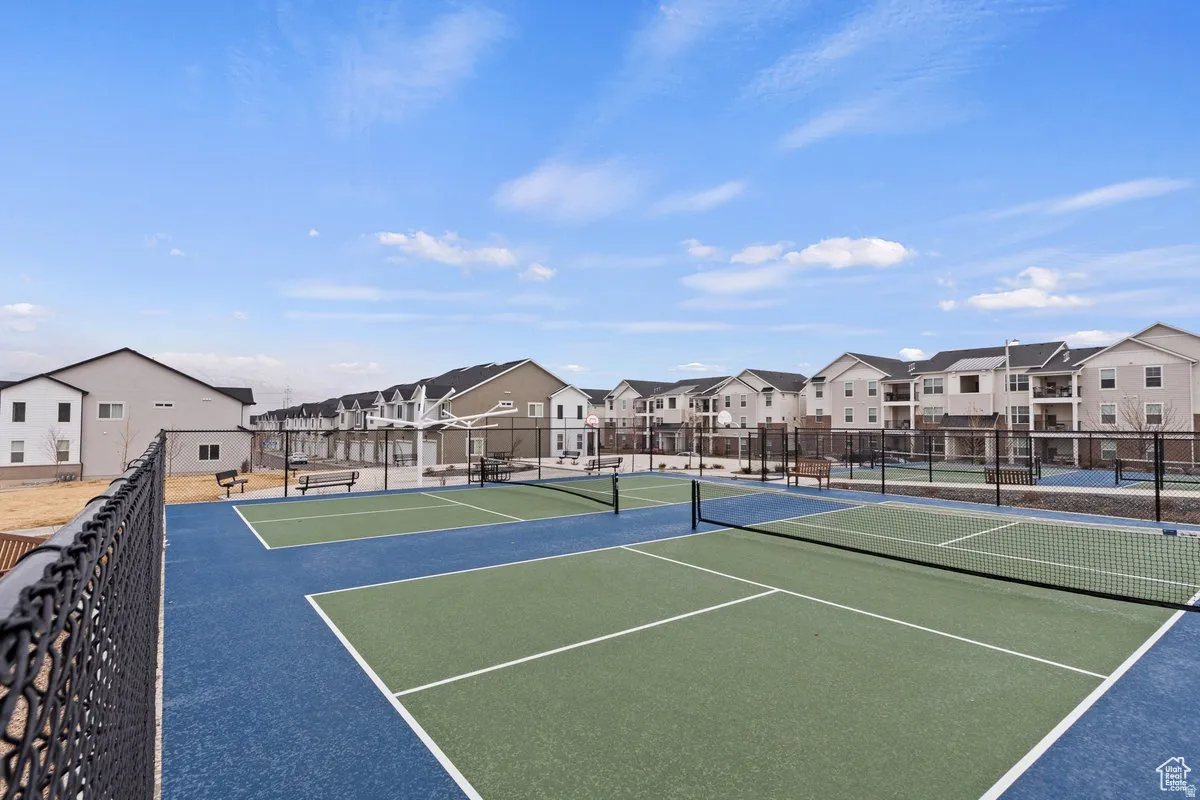Recreational court area featuring multiple blue and green playing surfaces, court nets, and perimeter fencing