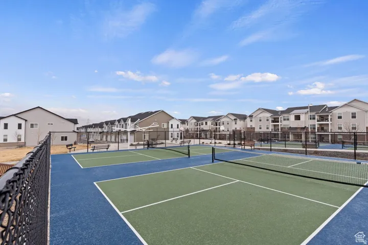 Recreational court area featuring multiple blue and green playing surfaces, court nets, and perimeter fencing