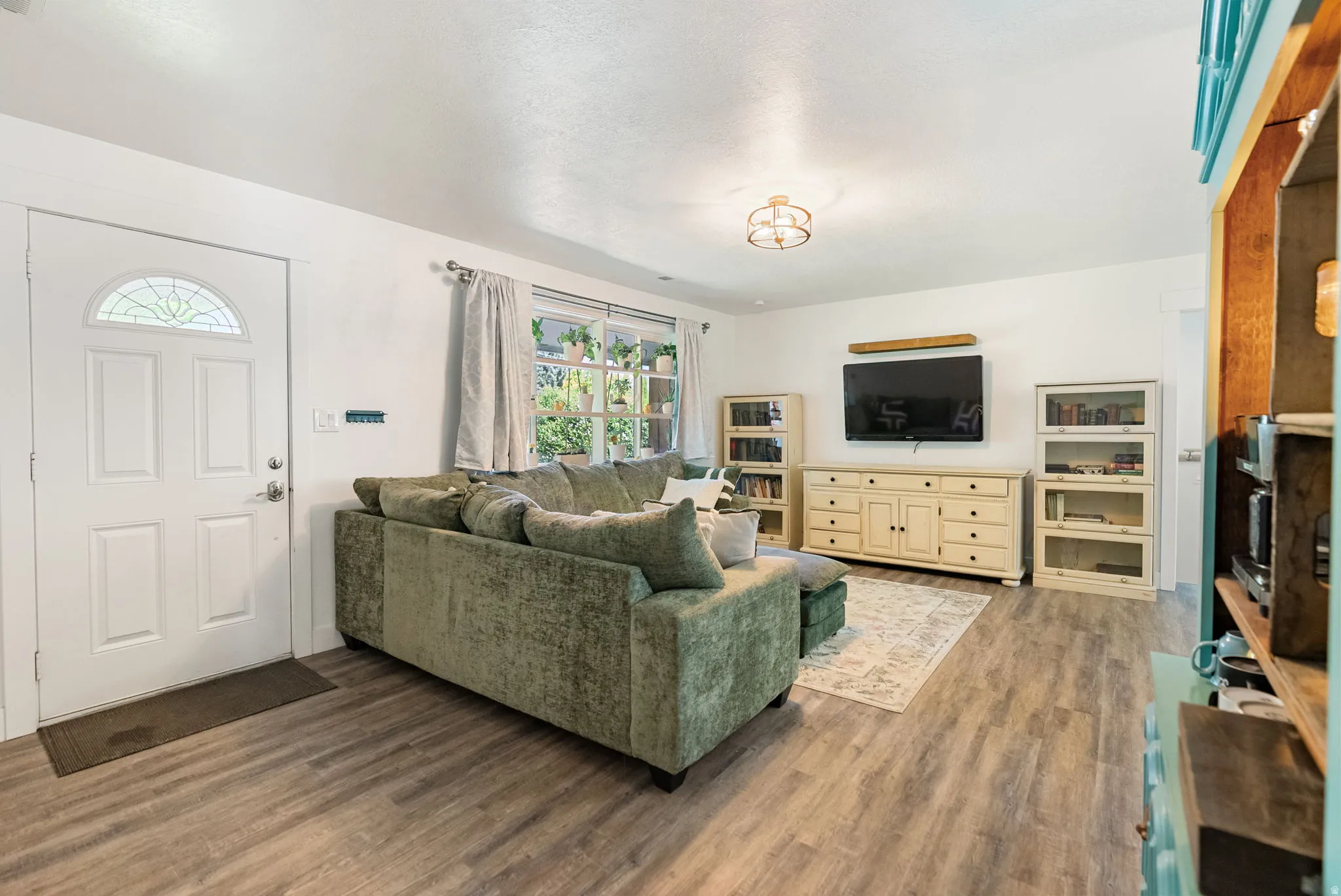 Living area featuring wood-finish flooring, a decorative entry door with an arched glass insert, and abundant natural light from multiple windows