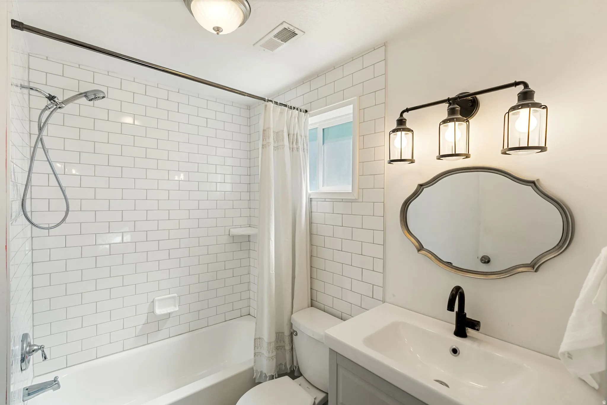 Bathroom featuring subway tile shower surround, integrated bathtub, and a vanity with a white basin sink