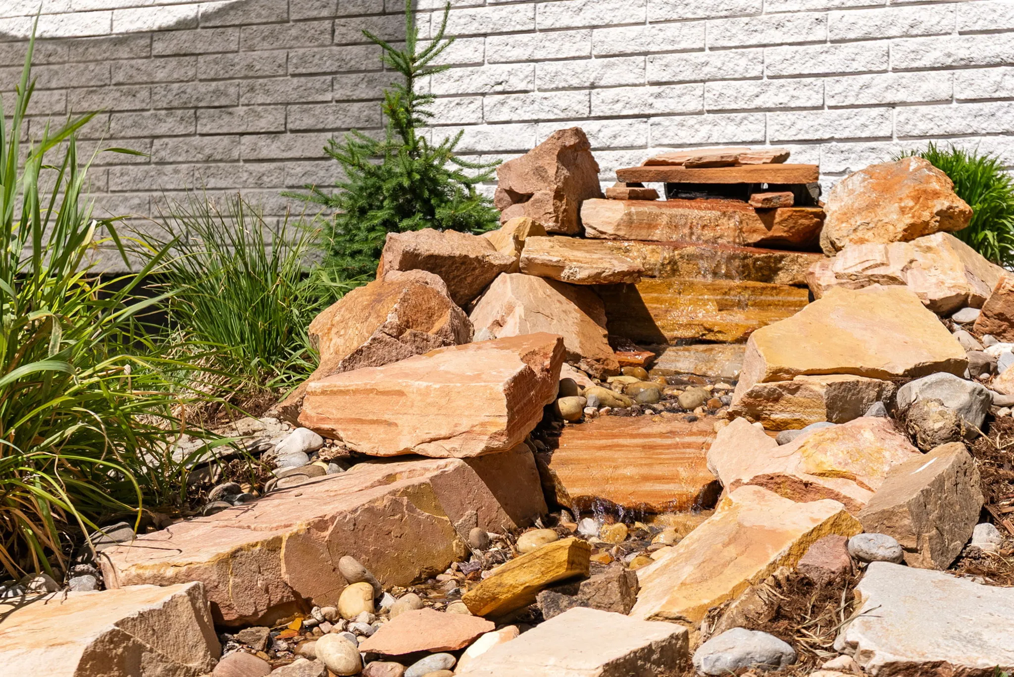 Water feature with natural stone boulders, tiered rock design, and integrated planting