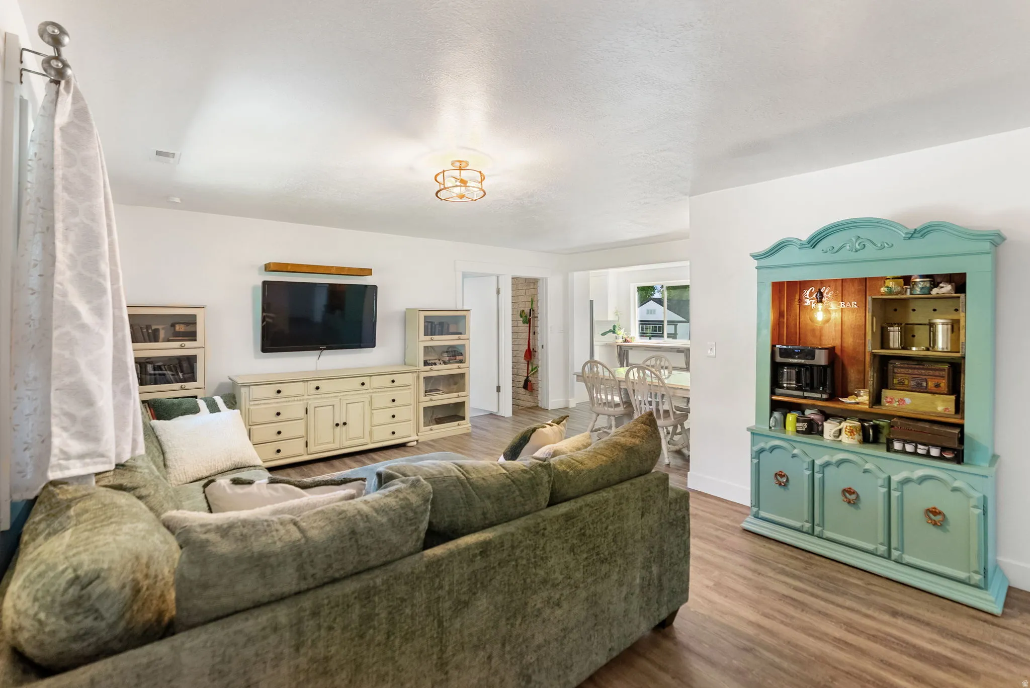 Bright living area featuring wood-finish flooring, a decorative ceiling light fixture, and a built-in display cabinet