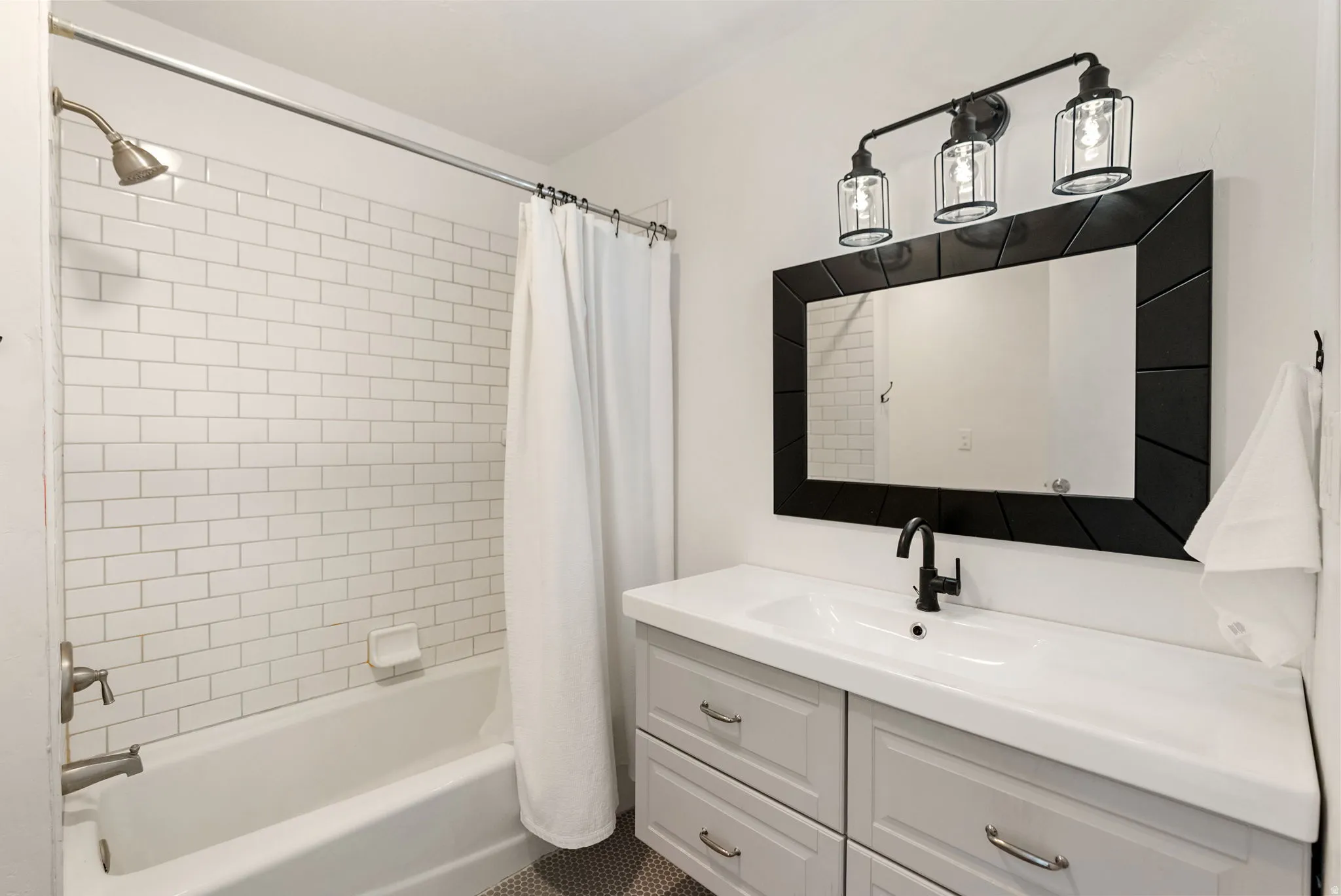Bathroom featuring a vanity with an integrated sink, a black framed mirror, and a three-light fixture