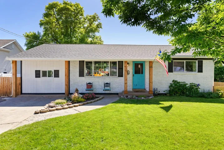 White brick exterior with black window shutters and a vibrant turquoise front door