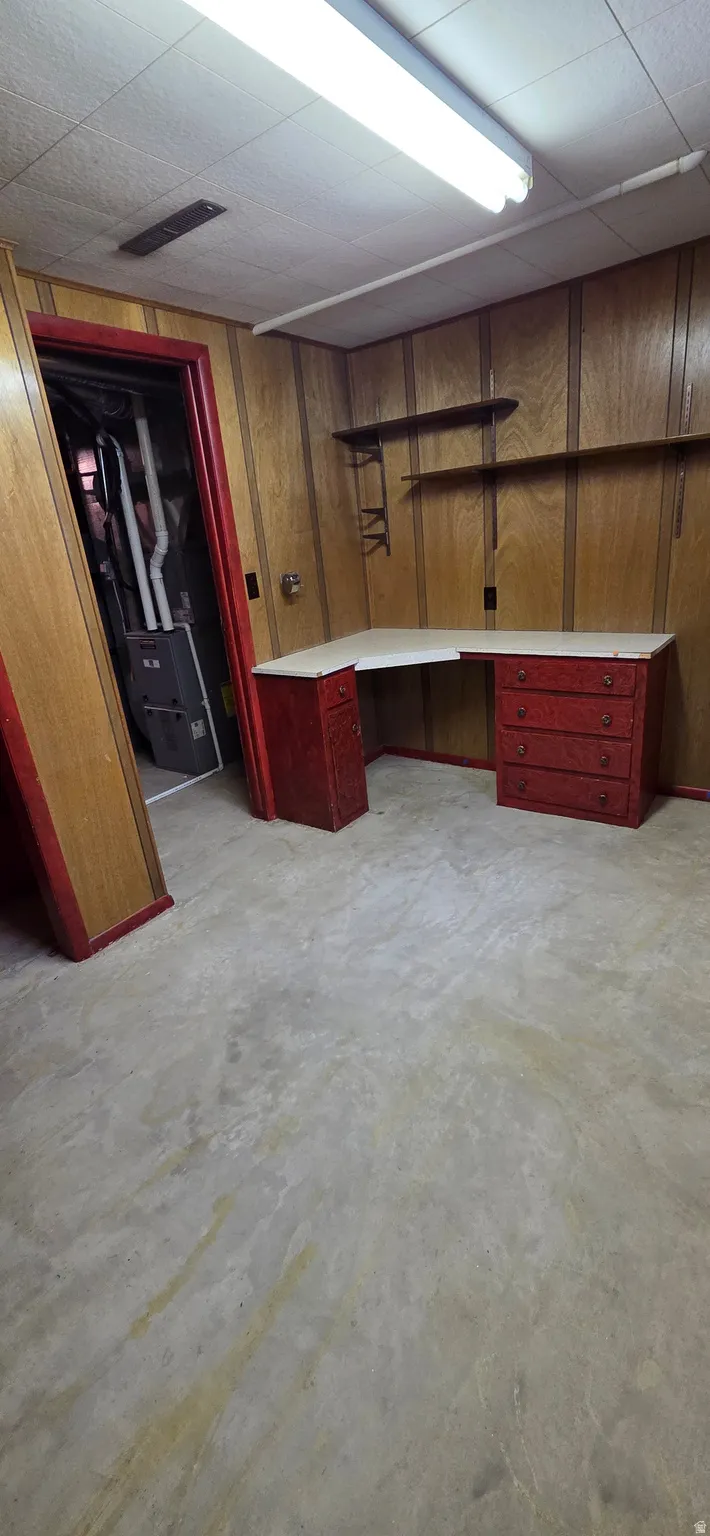 Room featuring wood paneling and a built-in L-shaped desk with red cabinetry