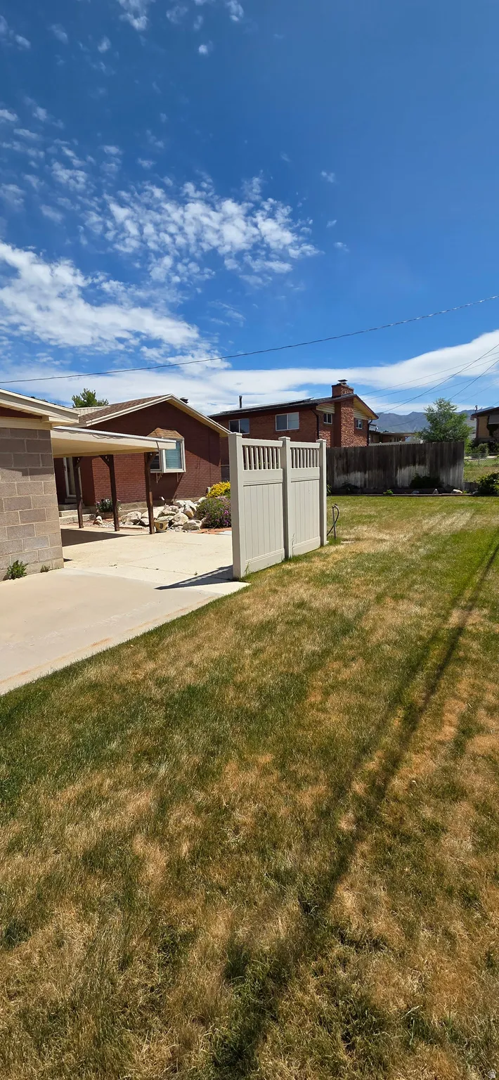 Expansive backyard featuring a concrete patio, a section of lawn, and a light-colored privacy fence