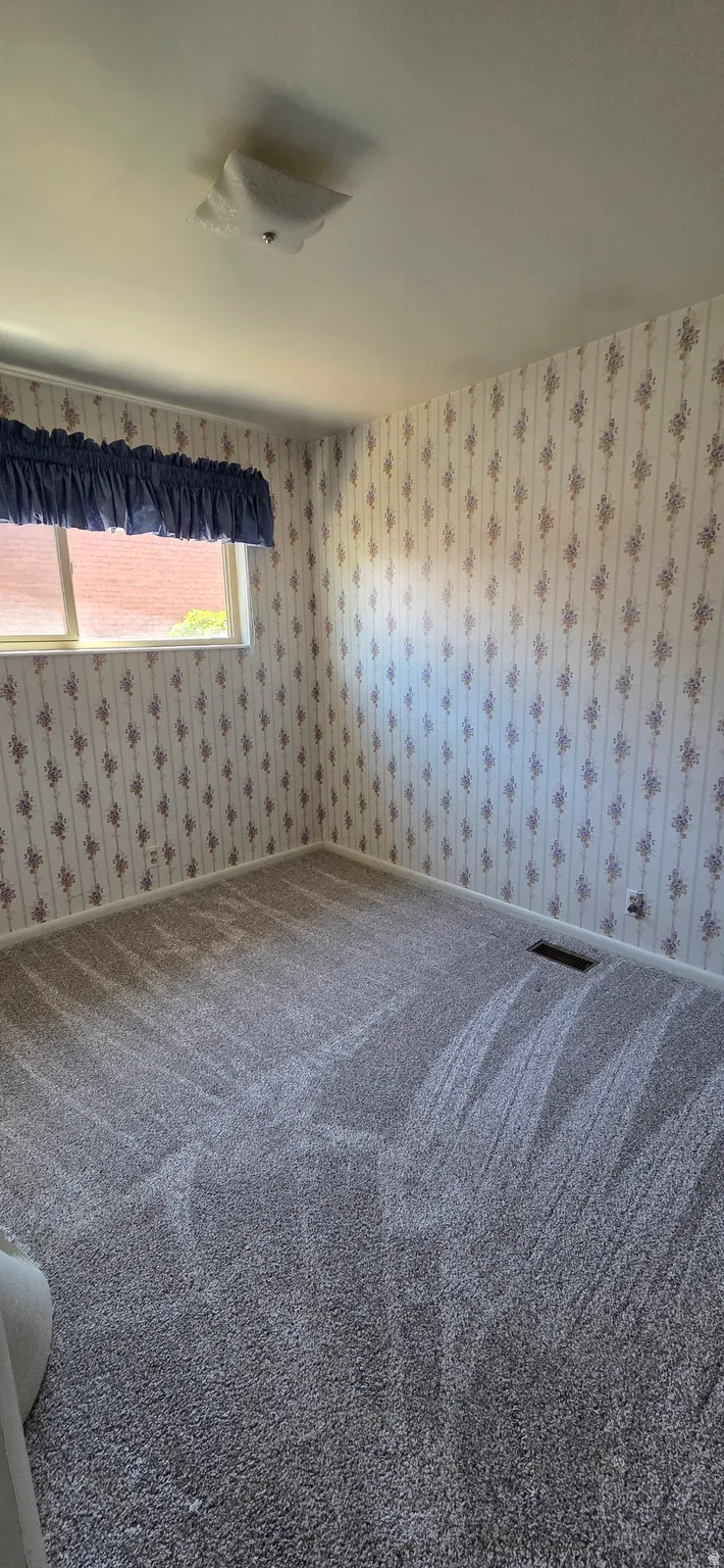 Carpeted interior room with patterned wallpaper