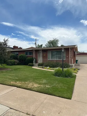 Brick exterior featuring a front lawn with established landscaping and a curved concrete walkway