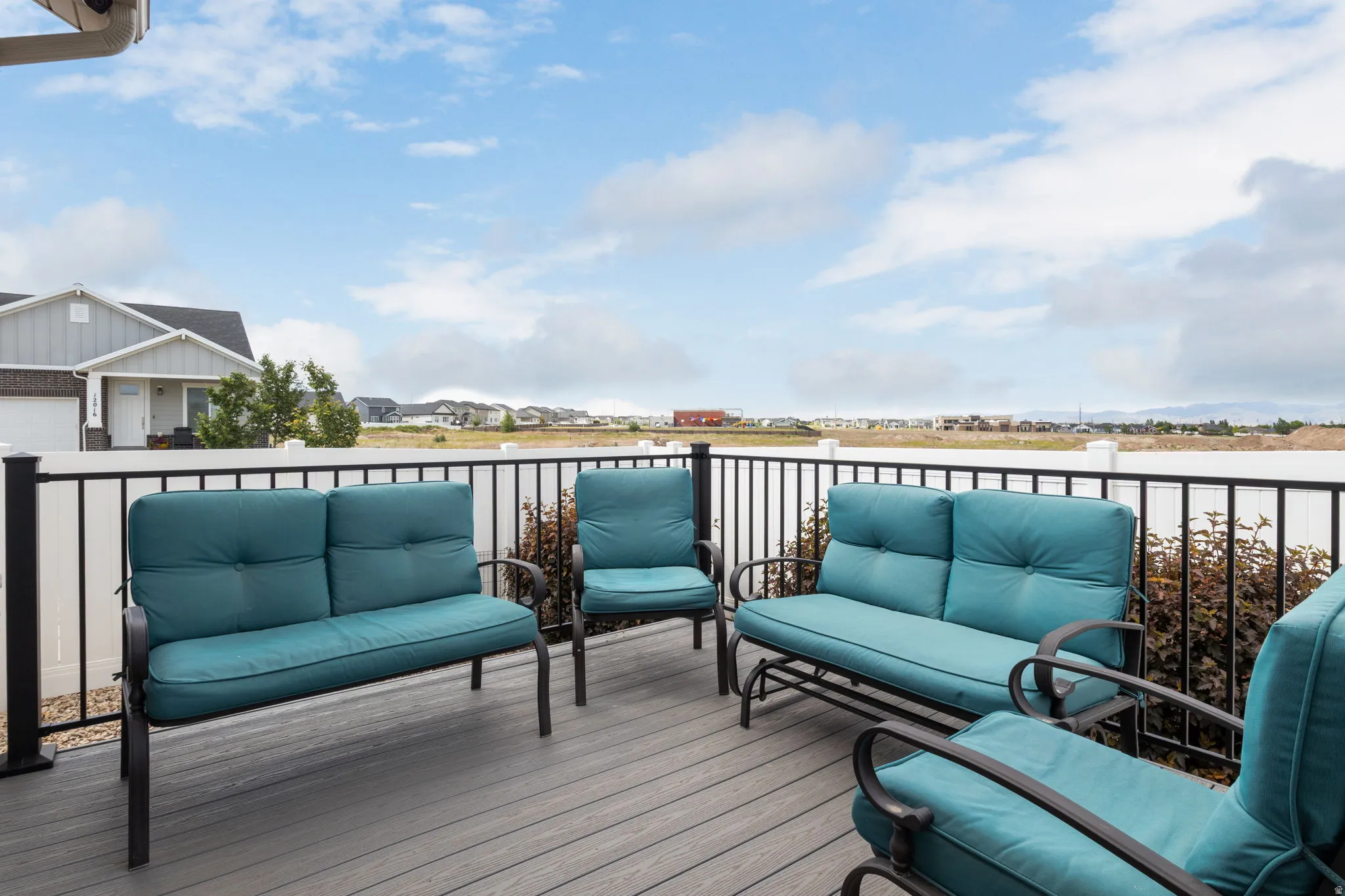 Spacious exterior deck featuring composite decking, black metal railings, and a white vinyl privacy fence