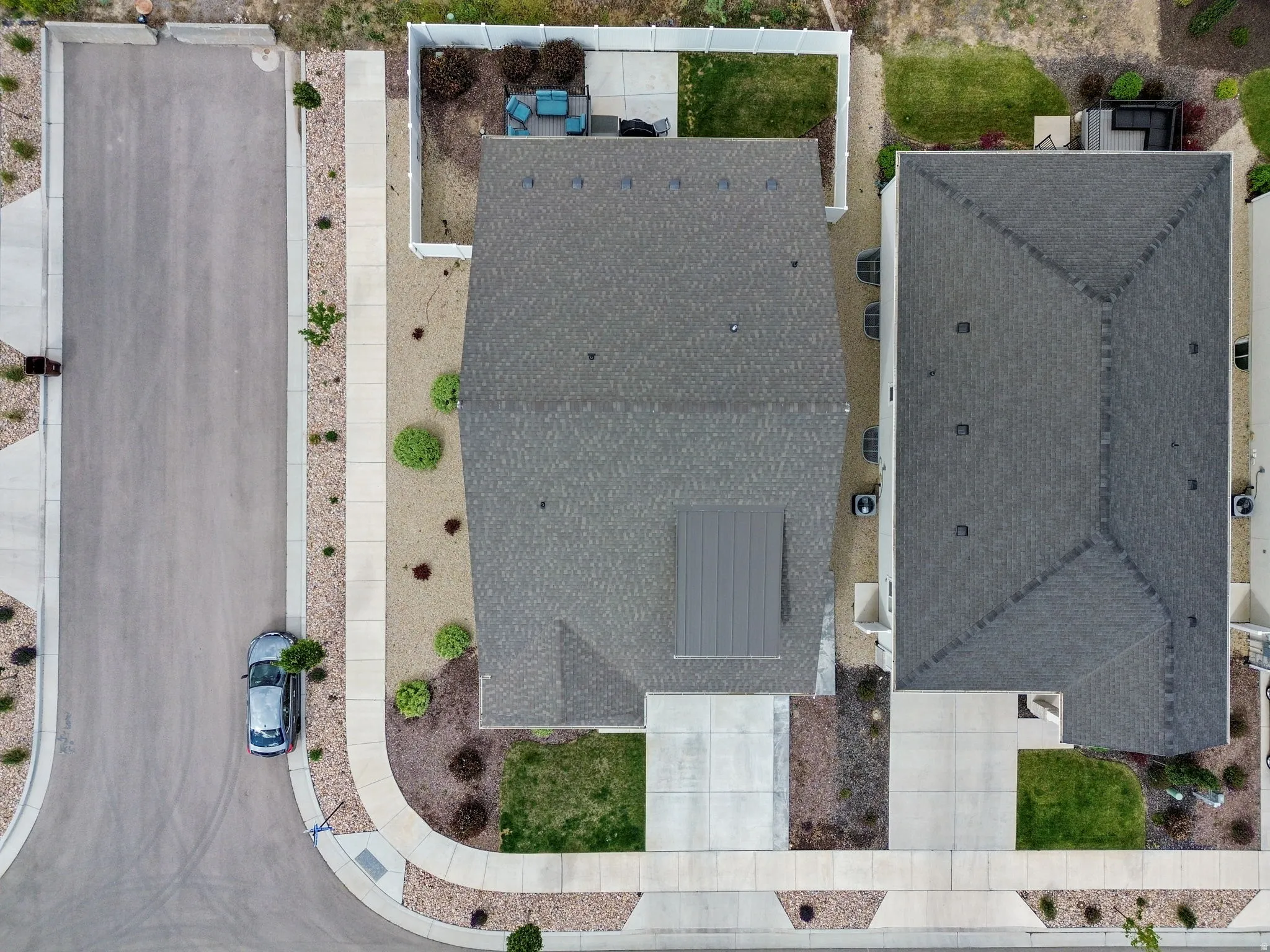 Aerial perspective showcasing a residential property with a dark shingle roof and a concrete driveway