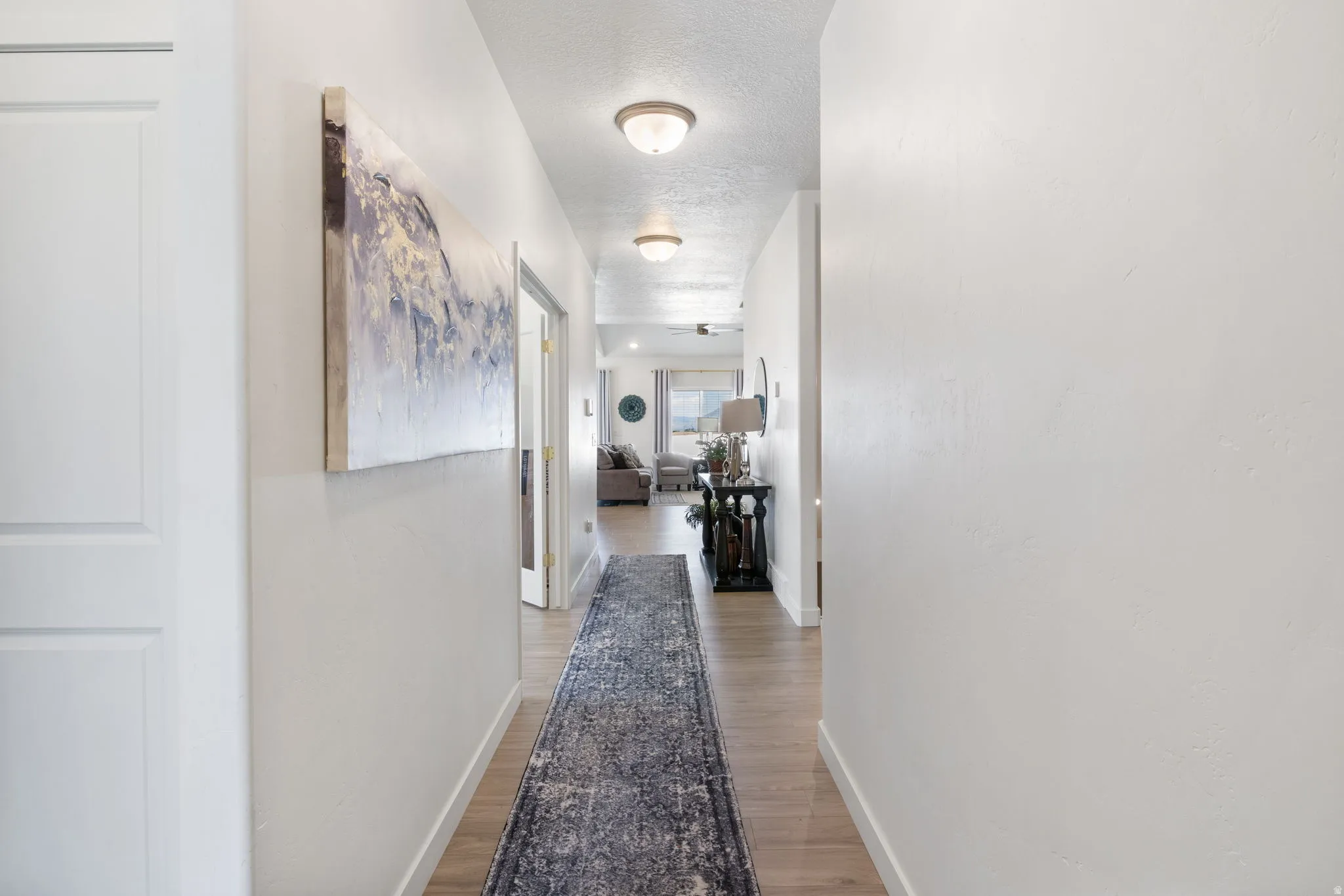 Hallway featuring wood-finish flooring, white walls, and flush-mount ceiling lighting