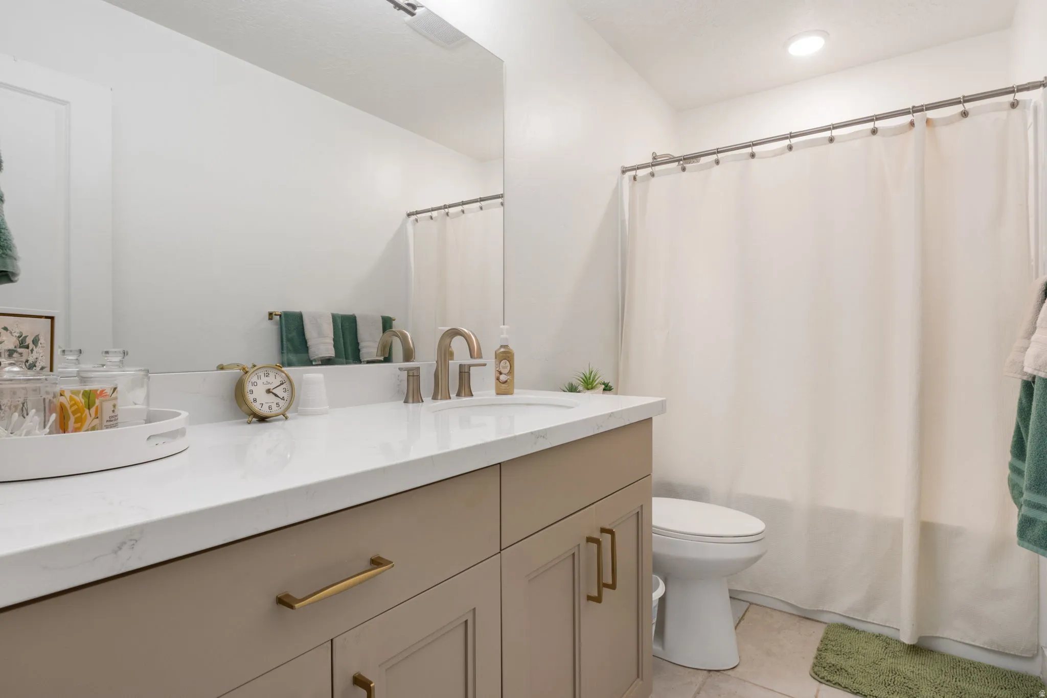 Bathroom featuring a single vanity with a white countertop and a brushed nickel faucet