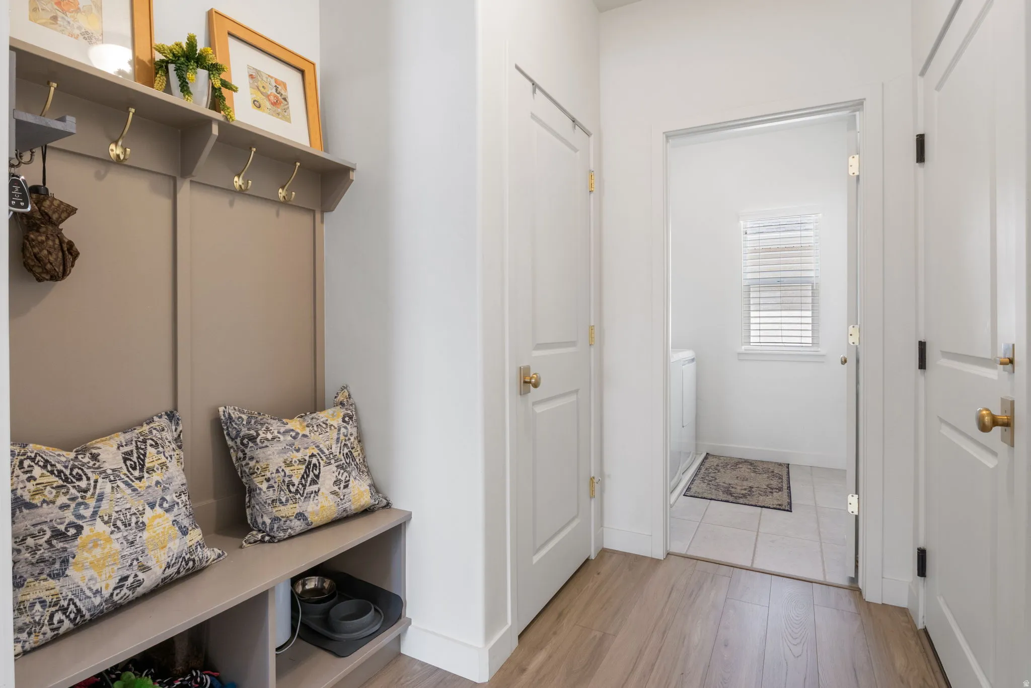 Entryway mudroom featuring built-in bench seating, overhead shelving, and wall-mounted coat hooks