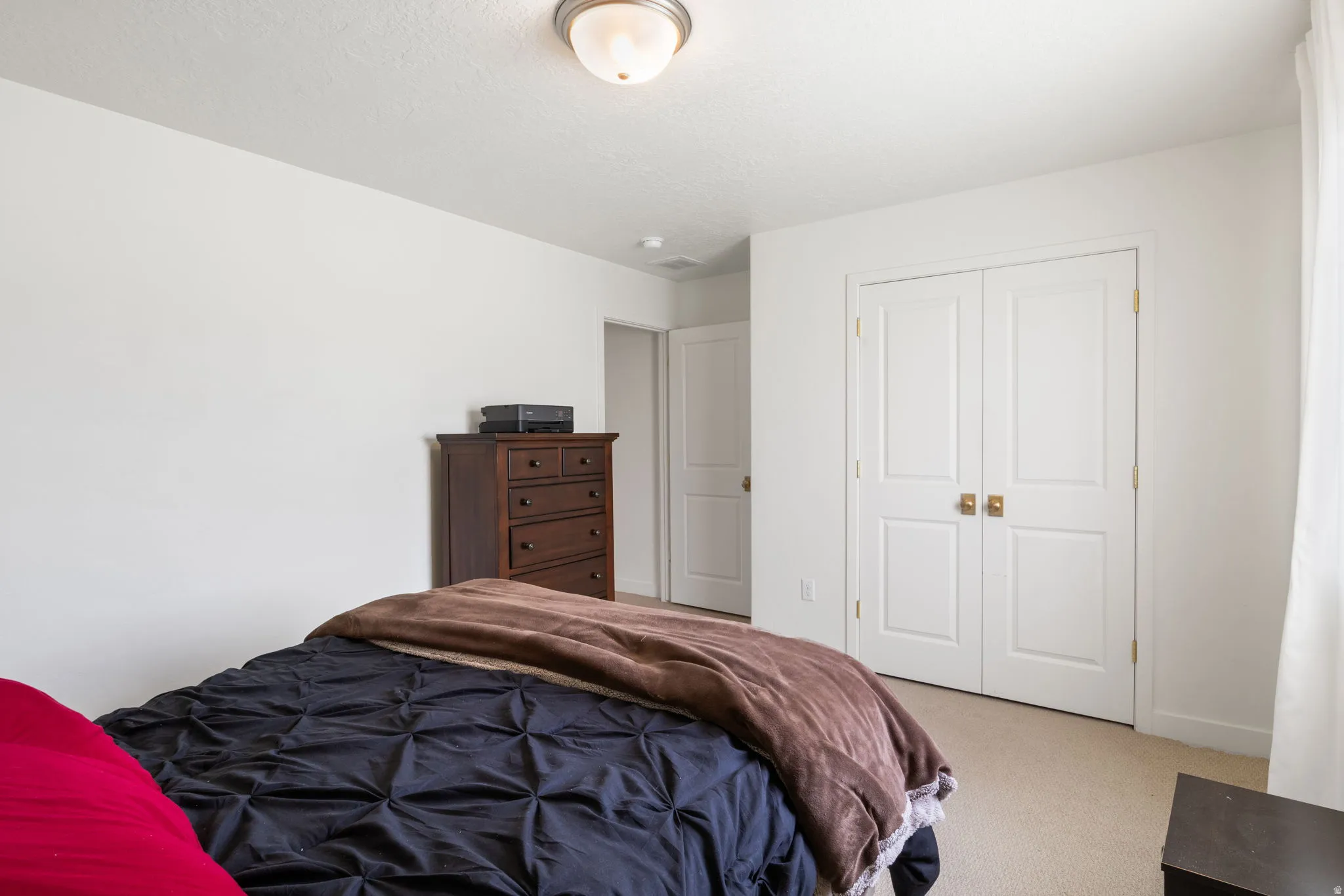 White interior walls with a textured ceiling, a flush mount light fixture, and carpet flooring