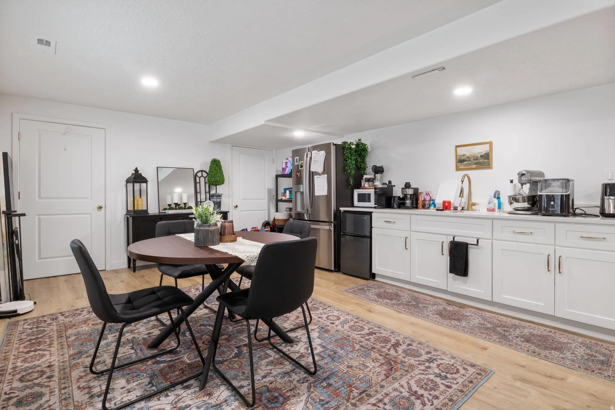 Full kitchen featuring white cabinetry, a gold-finish faucet, and wood-finish flooring